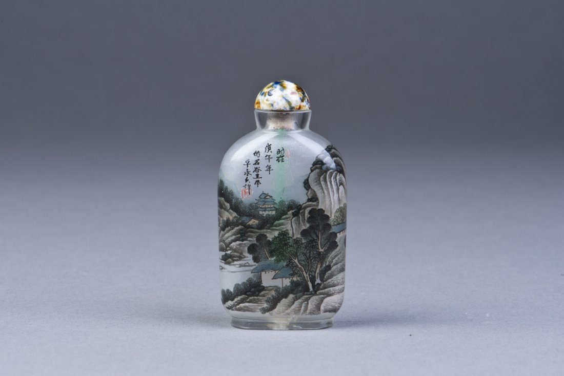 Inside Painted Glass Snuff Bottle: A well-hollowed Glass Snuff Bottle of flattened rectangular form with rounded shoulders, depicting Chinese landscape overall, inscribed with seal and period, a multicolored lid. Height 3.25'' Width 1.