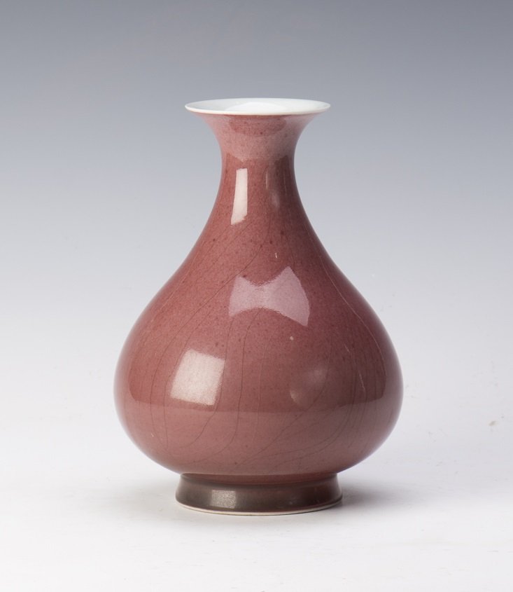 A RED GLAZED PORCELAIN VASE: A red glazed porcelain vase of globular form with wide flared mouth, and rasied inverted base. Diameter 6" Height 8.5"