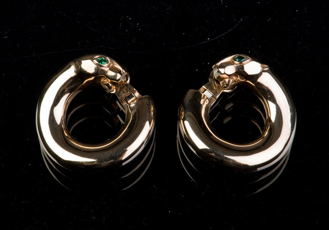 A PAIR OF CARTIER GOLD HOOP EARRINGS WITH EMERALD: A pair of gold hoop earrings, front side terminating in the form of the head of a snake, decorated with emerald stones as eyes, openwork design on the back side.