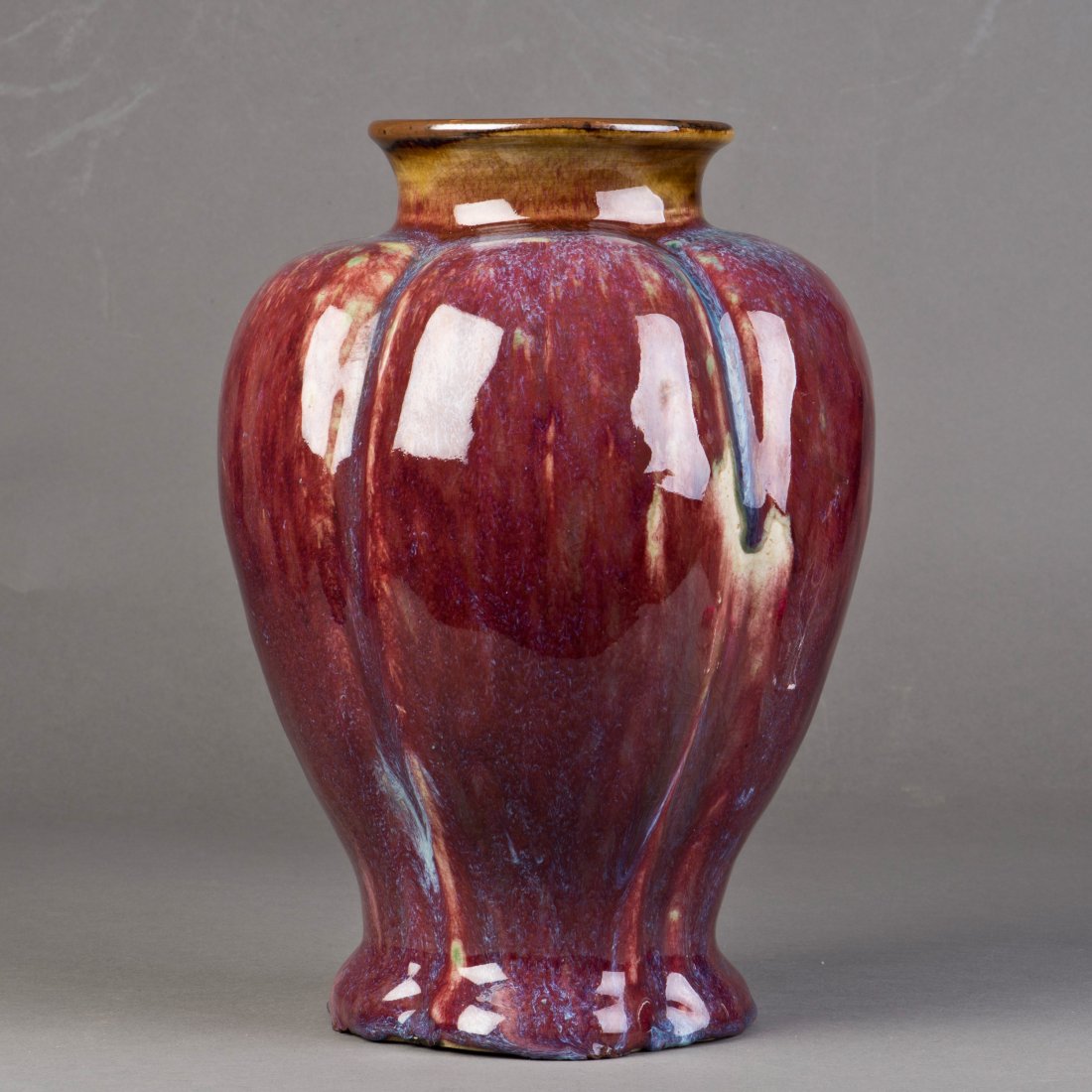 A FLAMBE GLAZED POMEGRANATE VASE: A flambe-glazed pomegranate vase supported on a flared foot and a rounded body and shoulder, rising to a short neck and a flared mouth. Height 11.5" Width 7"