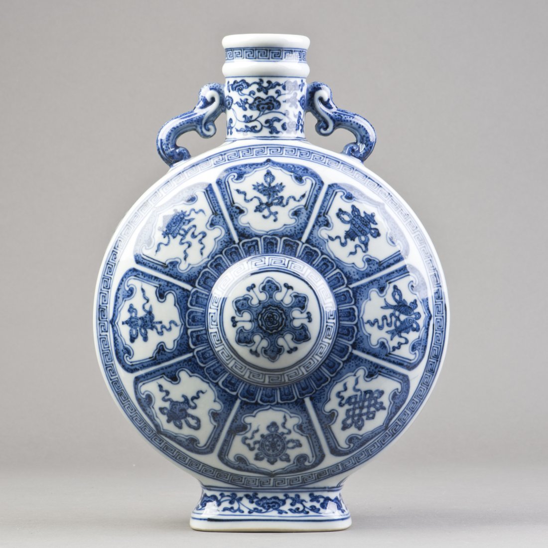 A BLUE AND WHITE PORCELAIN MOONFLASK VASE: A classic Chinese blue and white moonflask porcelain vase, decorated with the decoration comprised of eight auspicious symbols and the center medallion enclosed by two circles of lappets, the short sl
