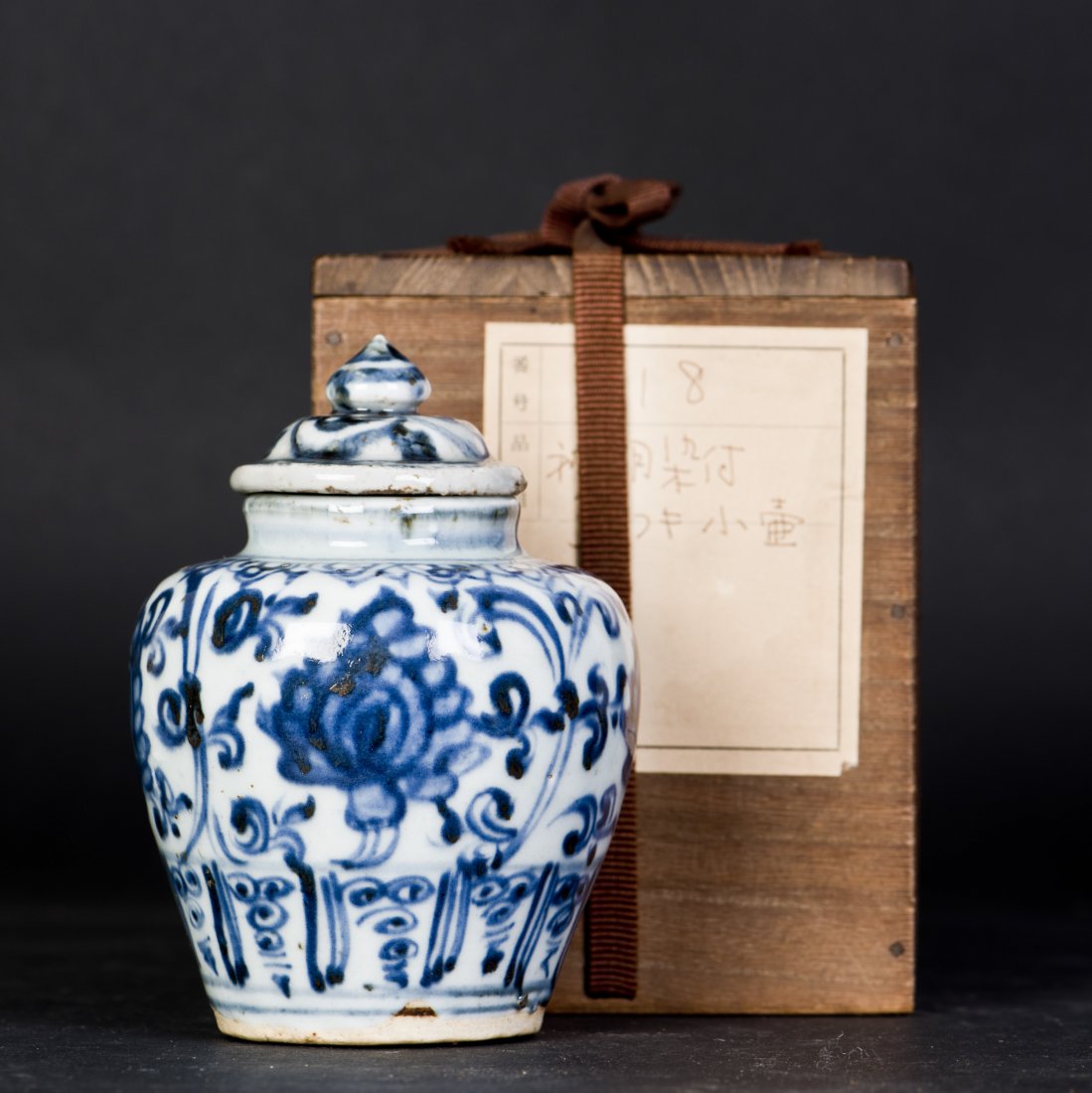 A BLUE AND WHITE PORCELAIN JAR WITH LID, MING DYNASTY: The oviform blue and white porcelain jar decorated with flowers and tendrils and foliages on the wall and its matching lid, visible natural wear and tear on the exterior and stains on the inside, base