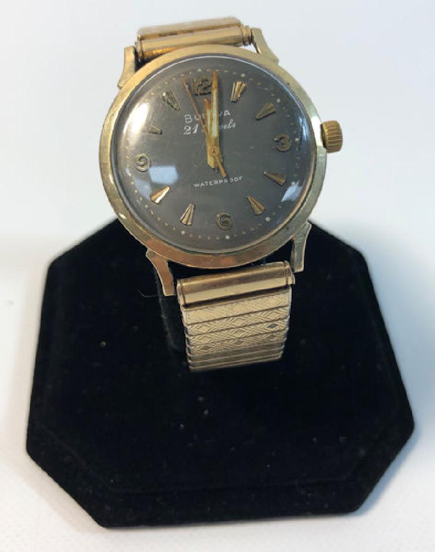 BULOVA WRIST WATCH ~ 21 JEWEL MOVEMENT. STRETCH BAND: BULOVA WRIST WATCH ~ 21 JEWEL MOVEMENT. STRETCH BAND (GOLD TONE METAL).TAPERED GOLD TONE HANDS/INDICATORS. 10KT RGP WATERPROOF CASE. NUMBERED 306124AND STAMPED M2.