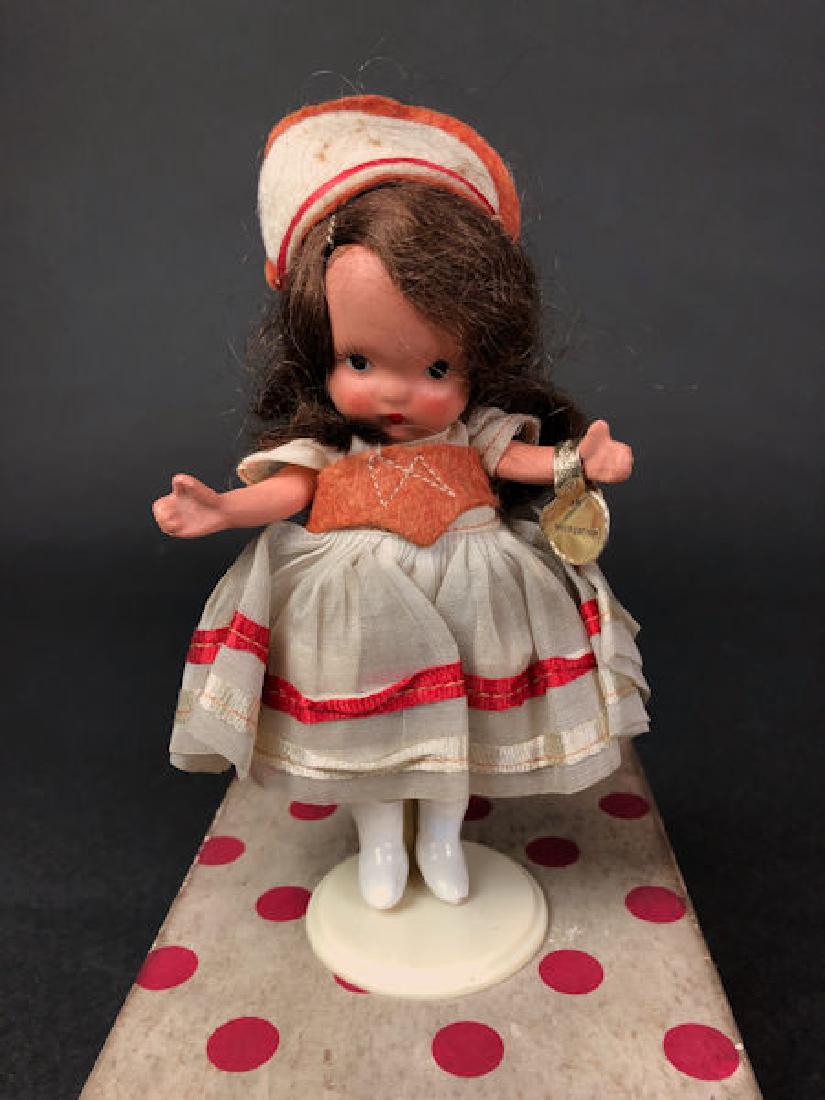 5½" STORYBOOK DOLL IN ORIGINAL COSTUME. "STORY: 5½" STORYBOOK DOLL IN ORIGINAL COSTUME. "STORY BOOK DOLL USA" MARK ON JOINTED PT BISQUE BODY WITH MOLDED SOCKS, PAINTED WHITE BOOTS AND GOLD FOIL WRIST TAG "STORYBOOK DOLLS". SMALL "NANCY ANN"