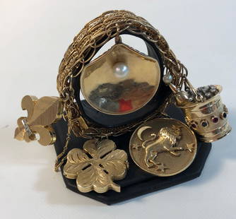 14KT VINTAGE CHARM BRACELET ~ 7: 14KT VINTAGE CHARM BRACELET ~ 7.5" X 0.625" , YELLOW GOLD FEATURING FIVE OVERSIZED CHARMS, 1.125" FOUR LEAF CLOVER LOCKET, 1.25" ROUND LEO CHARM, 1.5" CHAMPAGNE BUCKET CHARM, HIGH RELIEF DESIGN EMBELL