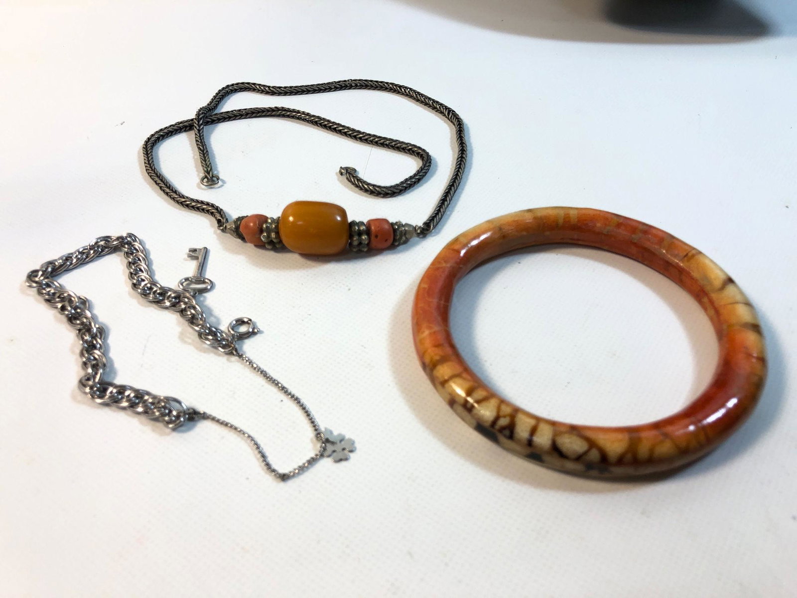 ASSORTED FASHION JEWELRY LOT: ASSORTED FASHION JEWELRY LOT ~ LOT INCLUDES: 3.25" TESSELATED BONE BANGLE (ORANGE/OFF-WHITE). DOUBLE KERB-LINK CHAIN BRACELET W/POLISHED FINISH AND KEY AND SHAMROCK CHARMS (0.385 TROY OUNCES TW), AND 