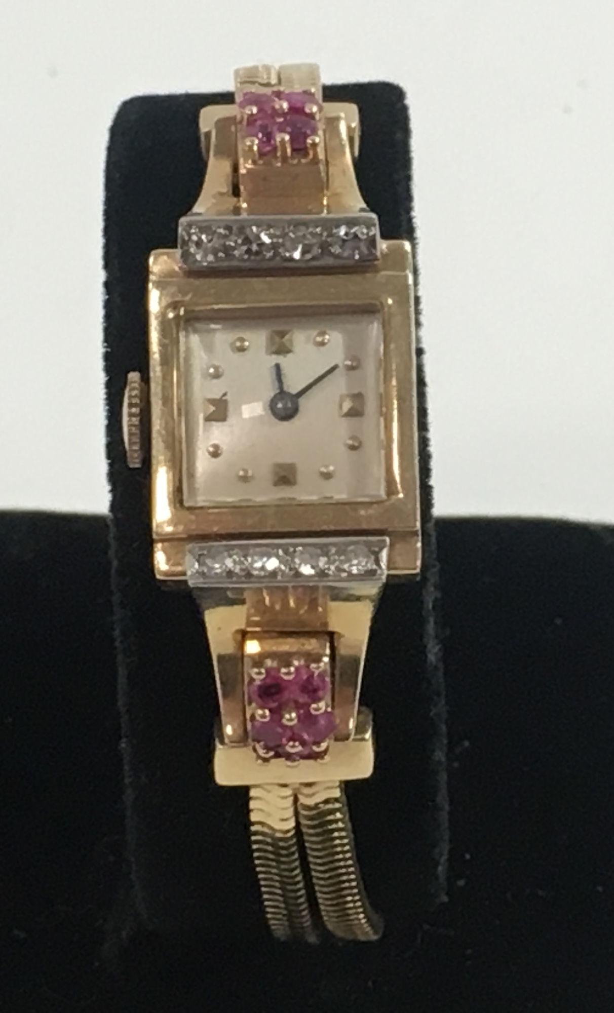 14KT YELLOW GOLD LADIES WATCH: 14KT YELLOW GOLD LADIES WATCH ~ GOLD BAND AND CASE, SERPENTINE LINK CHAIN BAND FEATURING A LINE OF DIAMONDS ON EACH SIDE OF THE CRYSTAL AND SIX RUBIES ON EACH BAND WHERE IT CONNECTS TO THE LINK (17.2 