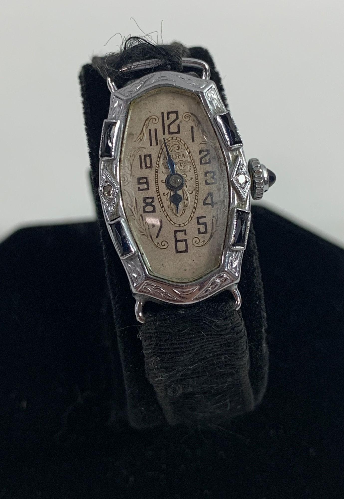 ANTIQUE LADIES WRIST WATCH: ANTIQUE LADIES WRIST WATCH ~ LIBERTY WHITE GOLD PLATE CASE CONTAINING 17 JEWEL MOVEMENT WINDS, SETS & TICKS, MADE BY ABRA, ON BLACK BAND W/ CASE CONTAINING TWO MELEE DIAMONDS AND TWO GEMSTONE BAGUETTE