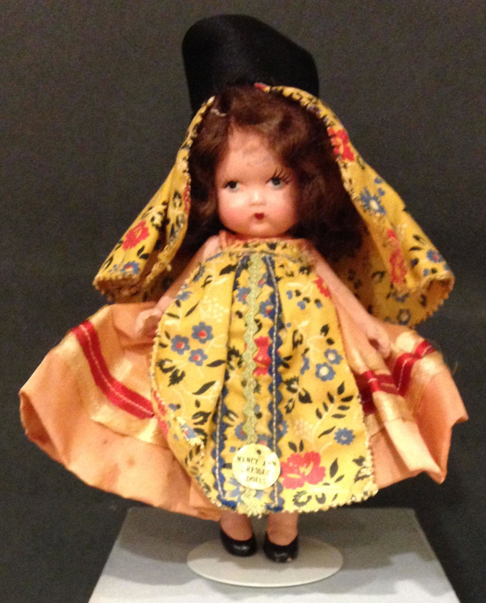 5¼" STORYBOOK DOLL IN ORIGINAL COSTUME: 5¼" STORYBOOK DOLL IN ORIGINAL COSTUME "PORTUGUESE". "MADE IN JAPAN 1146" MARK ON JOINTED PT BISQUE BODY WITH MOLDED SOCKS/BANGS, TOP KNOT UNDER WIG AND GOLD FOIL COSTUME STICKER "NANCY ANN DRE