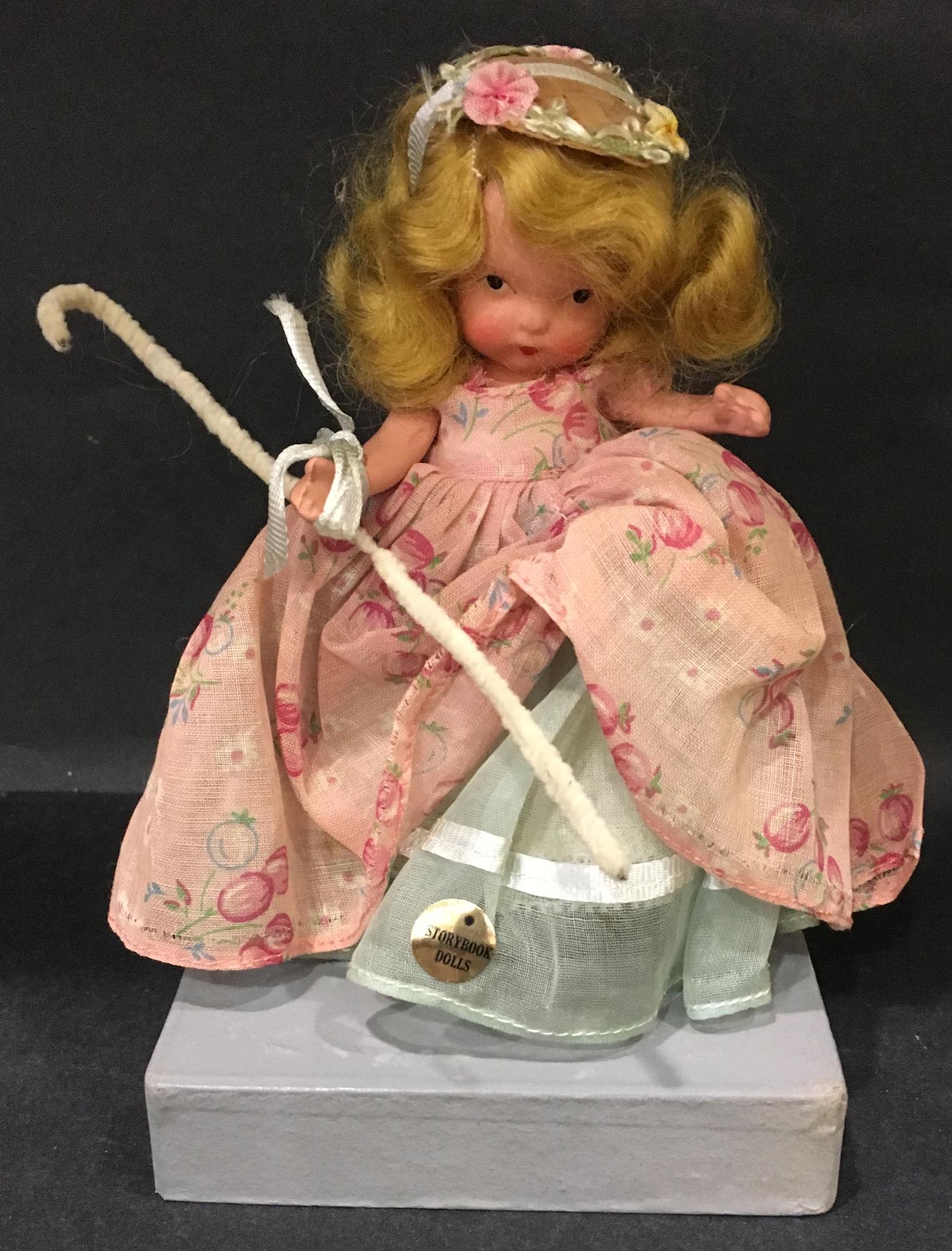 5½" STORYBOOK DOLL IN ORIGINAL COSTUME "LITTLE: 5½" STORYBOOK DOLL IN ORIGINAL COSTUME "LITTLE BO PEEP". "STORYBOOK DOLL" MARK ON JOINTED PT BISQUE BODY WITH MOLDED SOCKS/BANGS AND GOLD FOIL COSTUME STICKER.