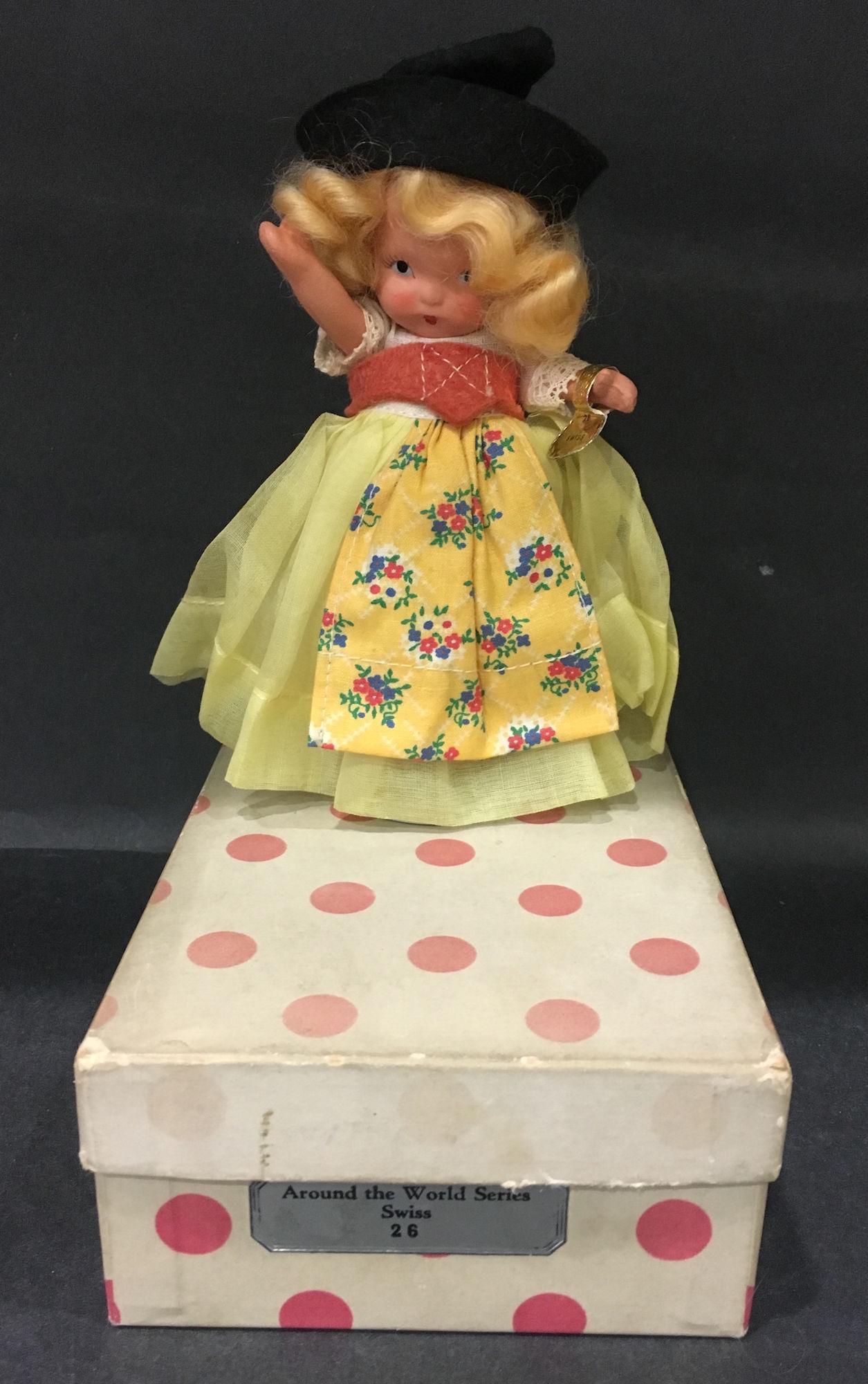5" STORYBOOK DOLL AROUND THE WORLD SERIES "SWISS" #26: 5" STORYBOOK DOLL AROUND THE WORLD SERIES "SWISS" #26 IN ORIGINAL COSTUME. "STORY BOOK DOLL USA" MARK ON JOINTED PT BISQUE BODY WEARING GOLD FOIL WRIST TAG. COMES IN WHITE BOX/RED DOTS WITH SILVER LAB