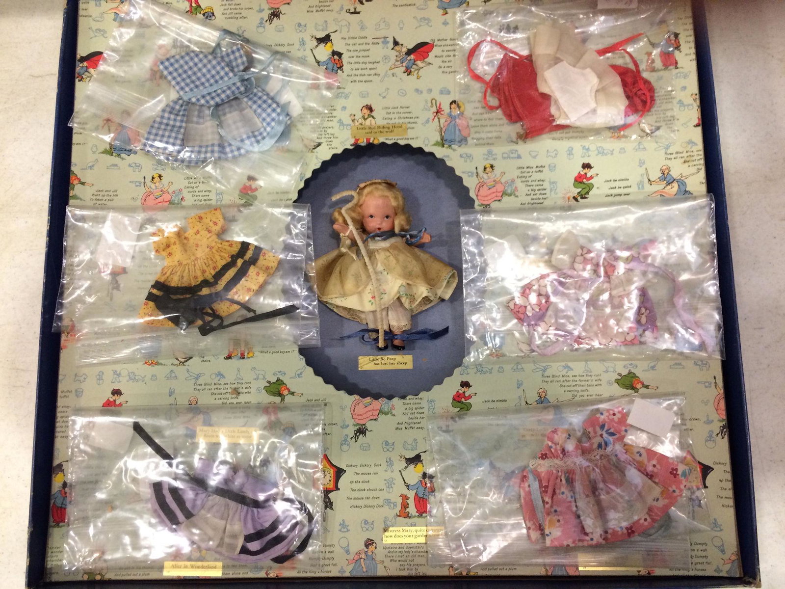 LARGE STORYBOOK SET #600 WITH 5½" STORYBOOK DOLL: LARGE STORYBOOK SET #600 WITH 5½" STORYBOOK DOLL IN CENTER. "JUDY ANN USA" MARK ON JOINTED PT BISQUE BODY WITH MOLDED SOCKS/BANGS AND COSTUMED AS "LITTLE BO PEEP". SOLID BLUE BOX AND NURSERY RH