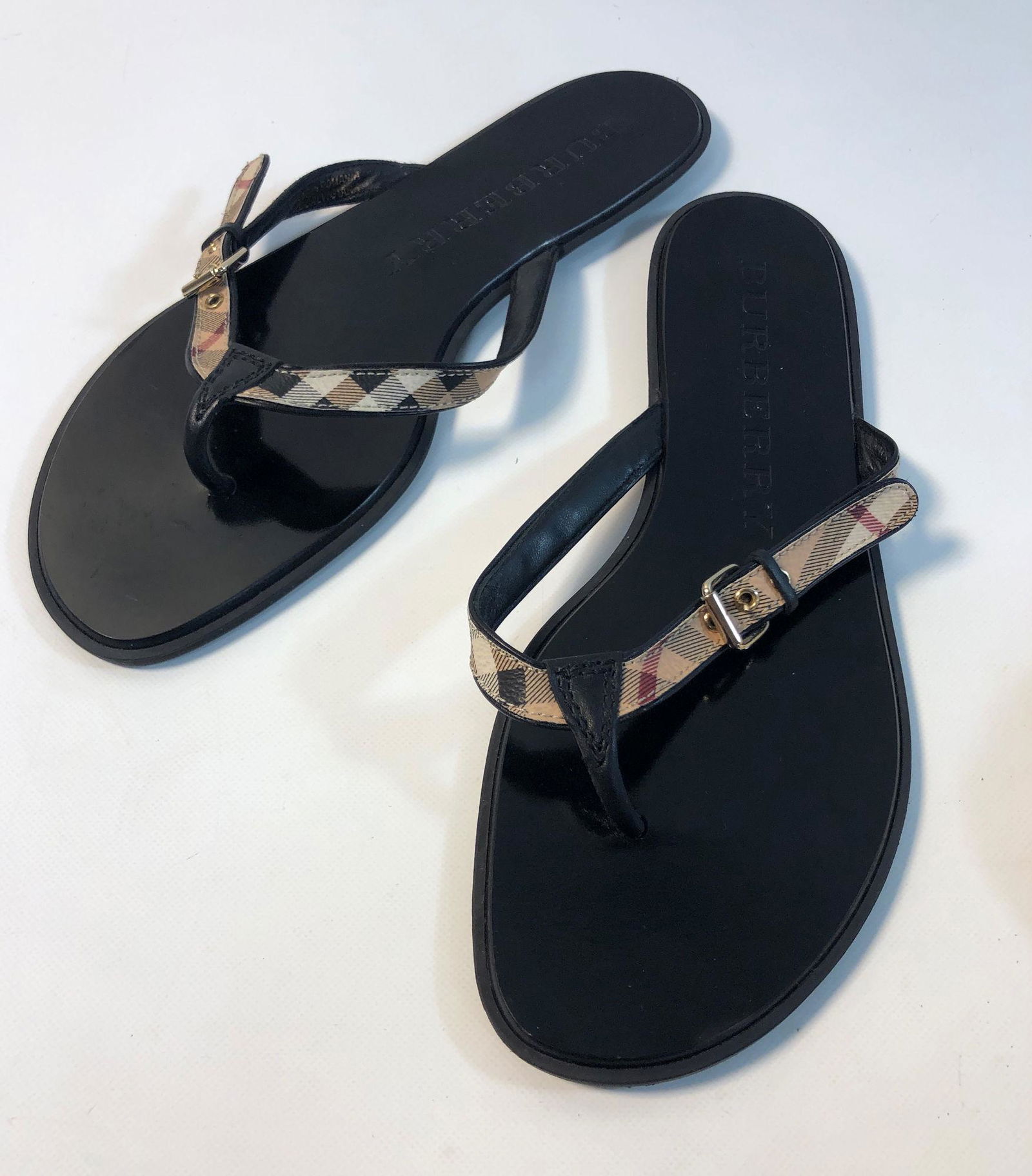 BURBERRY FLIP FLOPS: BURBERRY FLIP FLOPS ~ SIZE 40 EU, VERY GENTLY USED, BLACK LEATHER SOLES W/ CLASSIC PATTERN BUCKLE STYLE STRAPS, WITH BRANDED TRAVEL POUCH