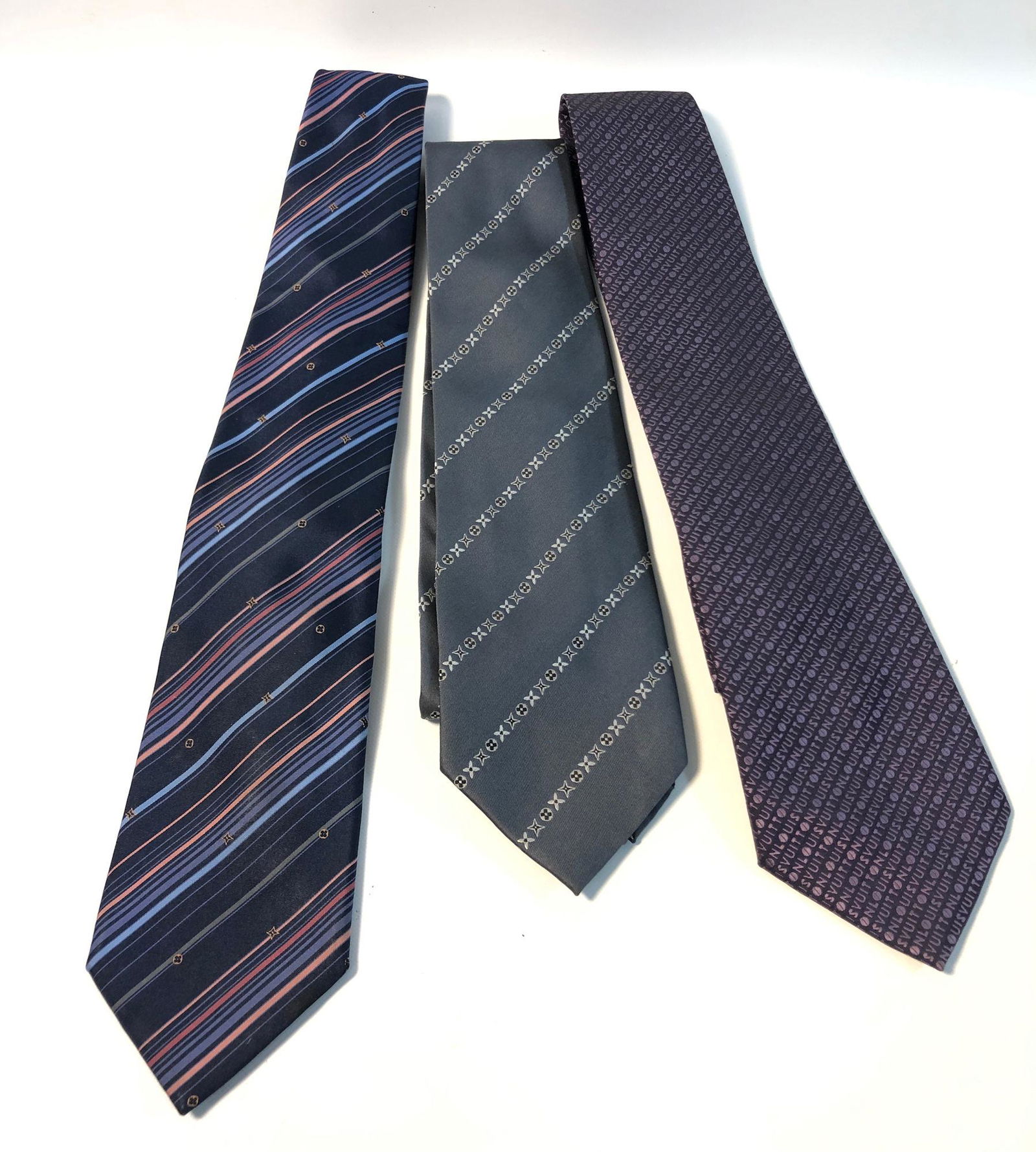 THREE LOUIS VUITTON TIES: THREE LOUIS VUITTON TIES ~ ALL 100% PURE SILK, LOT INCLUDES GREY TIE WITH LOUIS VUITTON SIGNATURE FLORAL PATTERN IN BLACK/SILVER TONE EMBROIDERY, RED TIPPING- LIKE NEW CONDITION, NAVY TIE WITH LIGHT B