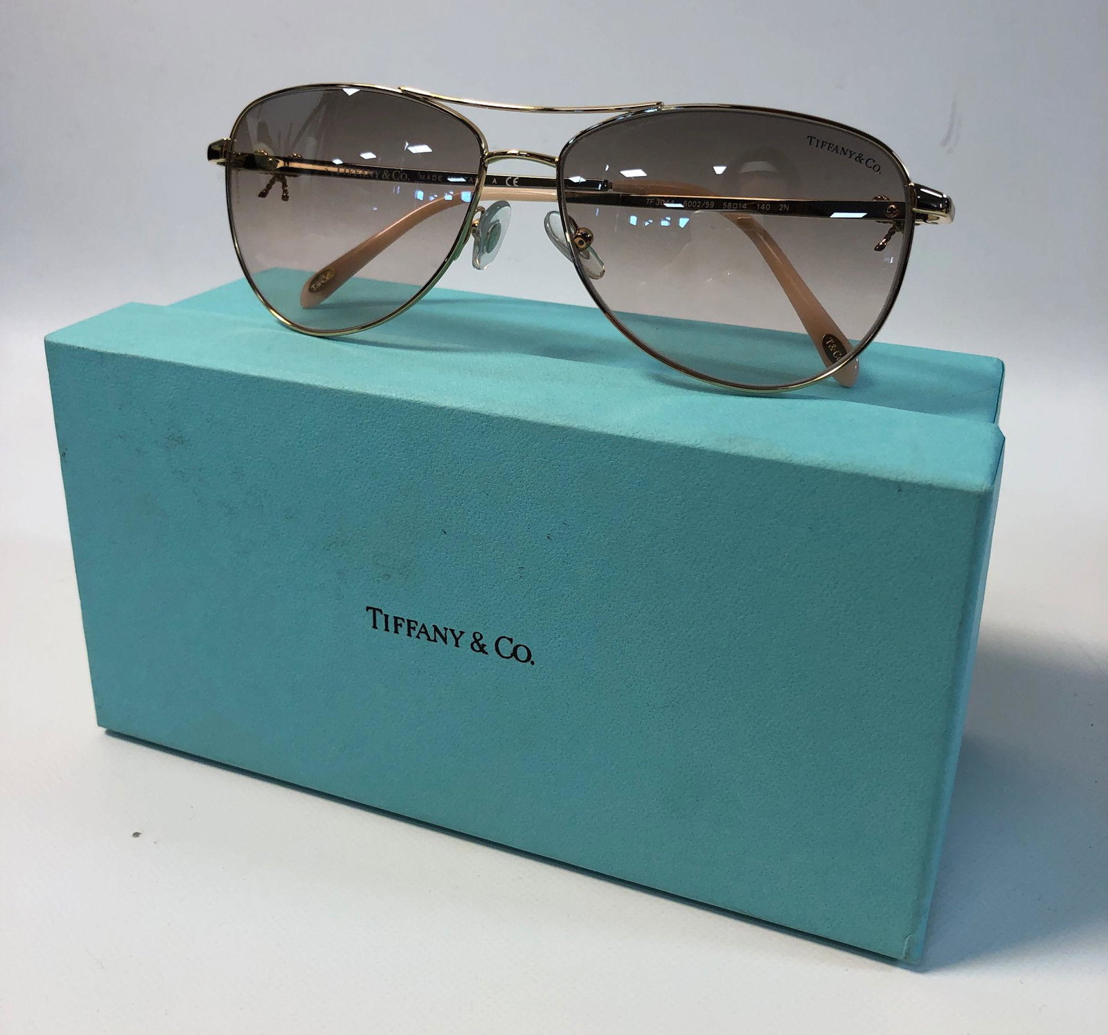 TIFFANY & CO. SUNGLASSES: TIFFANY & CO. SUNGLASSES ~ AVIATOR BOW SUNGLASSES, LIKE NEW CONDITION, GOLD TONE FRAMES WITH IRIDESCENT BLUSH PINK TEMPLE TIPS, ITALIAN MADE, LENSES HAVE A BLUSH PINK HUE, LOT INCLUDES, CERTIFICATE OF