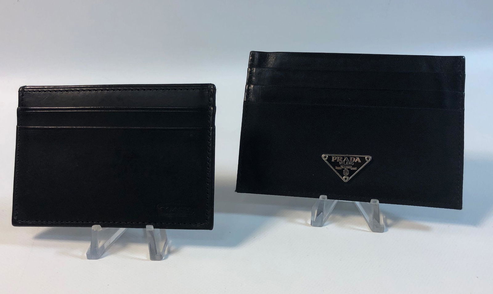 TWO BLACK LEATHER CREDIT CARD WALLETS: TWO BLACK LEATHER CREDIT CARD WALLETS ~ 4" X 2.75" FROM COACH W/FIVE POCKETS. 4.5" X 3.25" FROM PRADA W/SEVEN POCKETS. BOTH BRANDED.