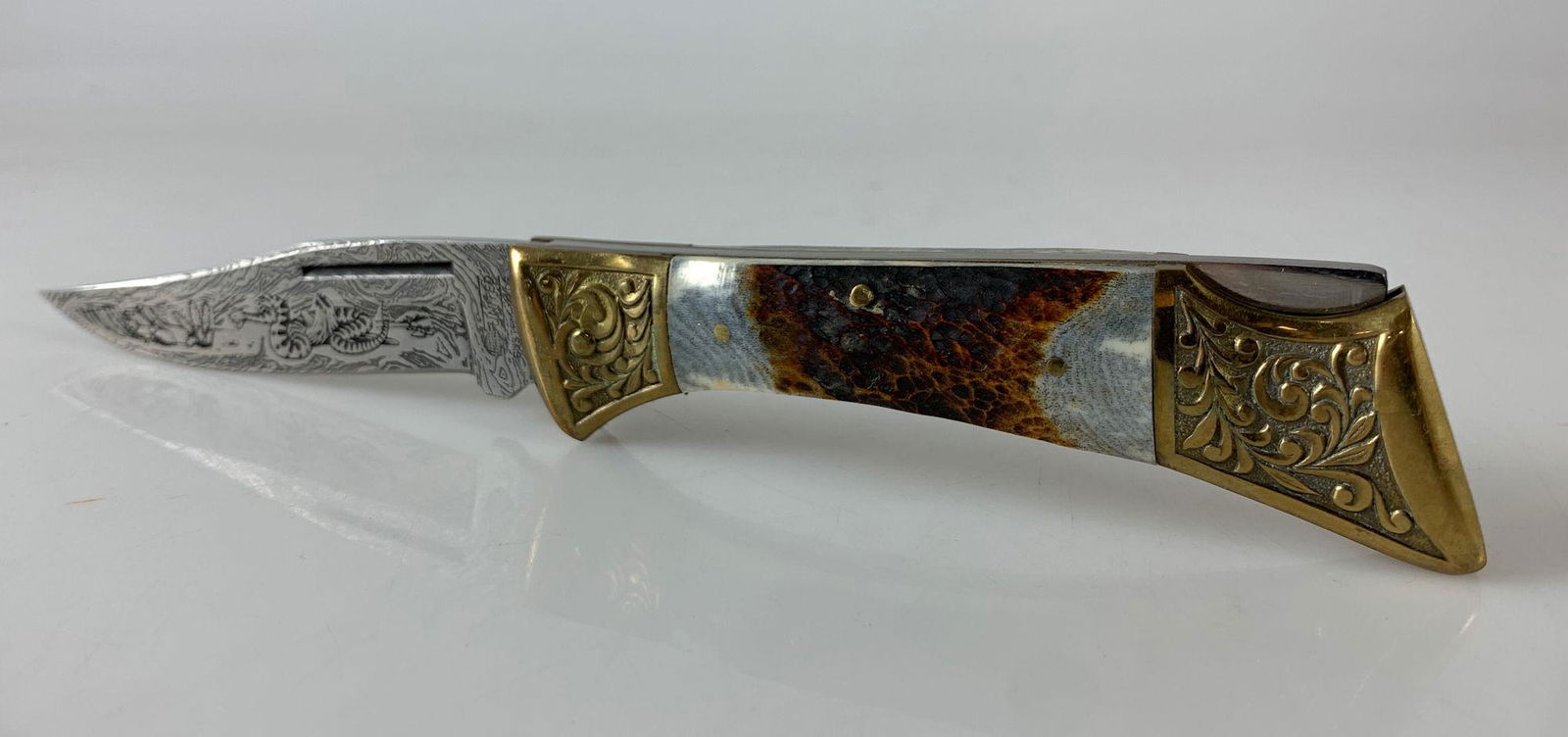 FOLDING KNIFE FROM UNITED: FOLDING KNIFE FROM UNITED ~ 7.25" TOTAL LENGTH. JAPANESE MADE (CUSTOM). NATURAL HORN SCALES. ETCHED STEEL BLADE FT. SNAKE MOTIF ON CALIFORNIA CLIP BLADE.