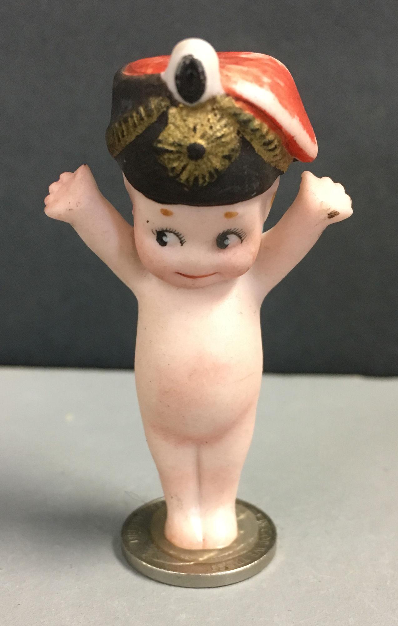 PRUSSIAN RIFLE BATTALION KEWPIE. 2 ½" BISQUE,: PRUSSIAN RIFLE BATTALION KEWPIE. 2 ½" BISQUE, RAISED ARMS, MOLDED AND PAINTED HELMET WITH TASSEL AND FIELD BADGE.