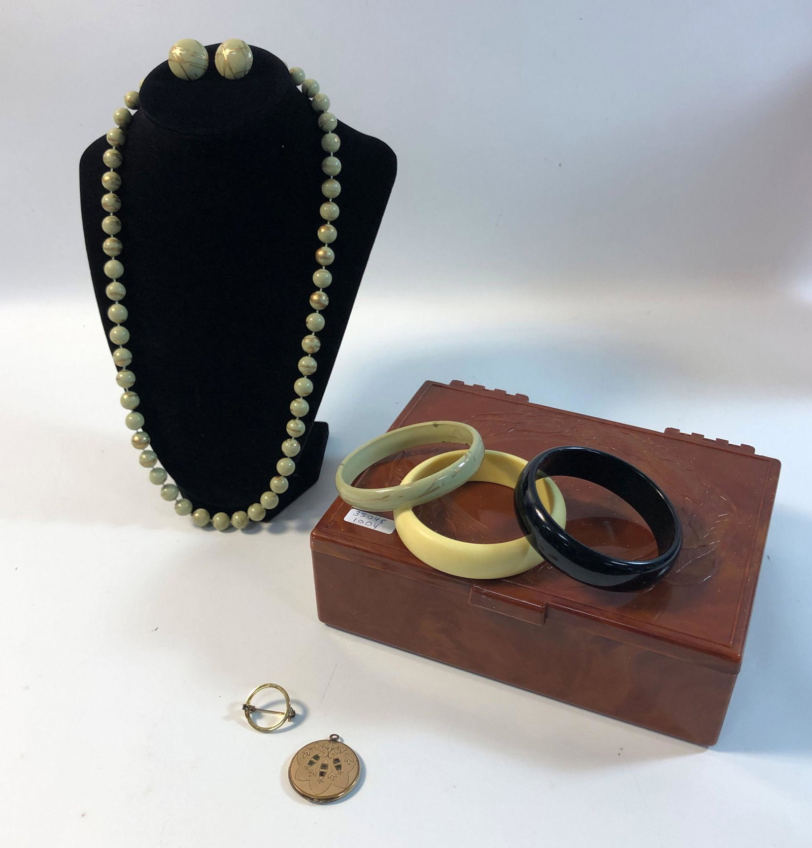 LOT OF VINTAGE FASHION JEWELRY IN SMALL BOX: LOT OF VINTAGE FASHION JEWELRY IN SMALL BOX ~ 3" BAKELITE BANGLES (OFF-WHITE AND BLACK). 0.75" GOLD TONE PIN. LOCKET STYLE PENDANT (VINTAGE) WITH ENGRAVED ART NOUVEAU STYLE PATTERN ON FRONT (AND INSET