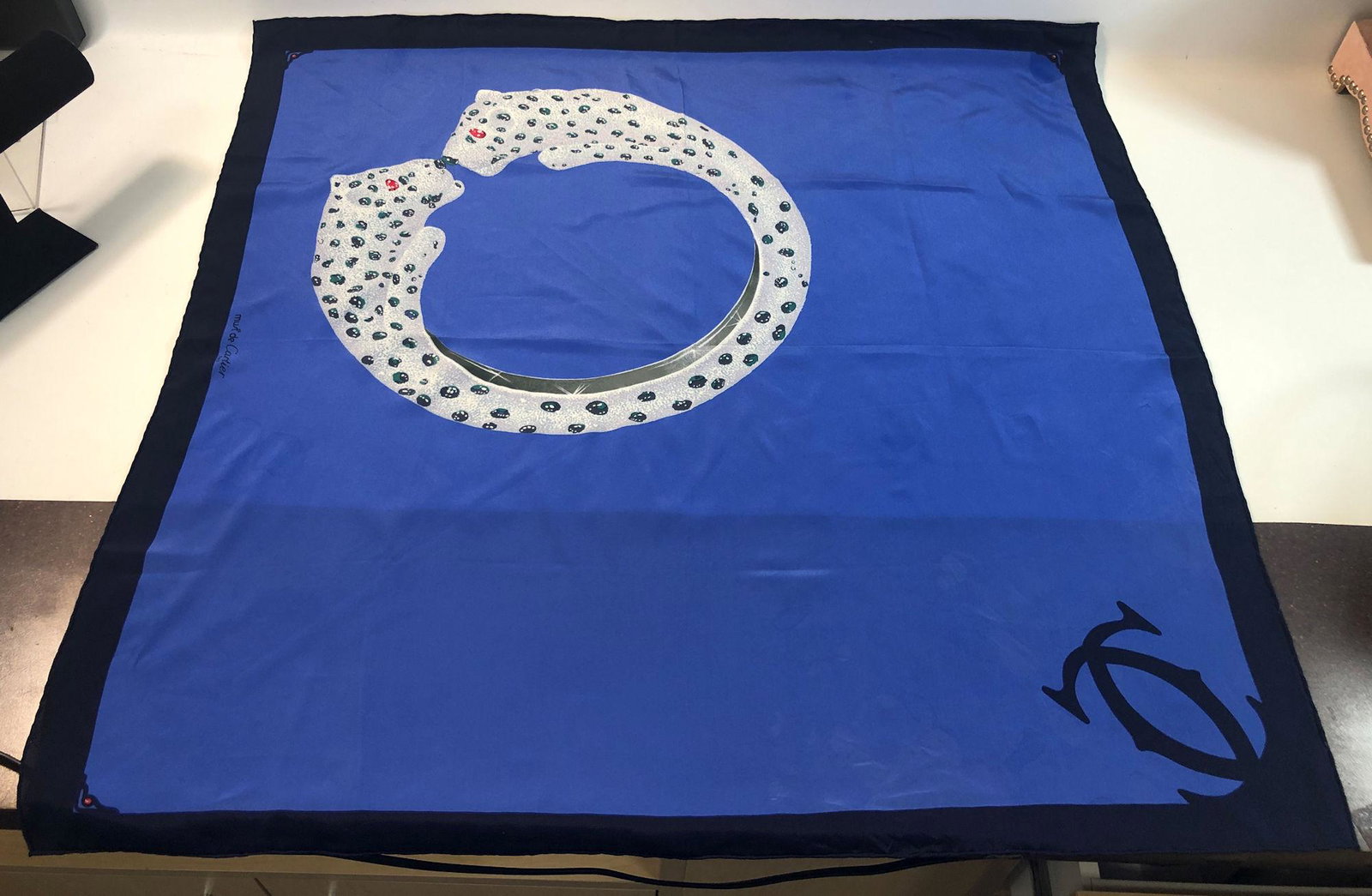 VINTAGE MUST DE CARTIER SILK SCARF: VINTAGE MUST DE CARTIER SILK SCARF ~ DESIGN FEATURES SIGNATURE PANTHER BRACELET MOTIF ON COBALT BLUE BACKGROUND SURROUNDED BY NAVY BLUE BORDER, DOUBLE MONOGRAM "C" APPOSES BRACELET, SQUARE 32" X 32" ,
