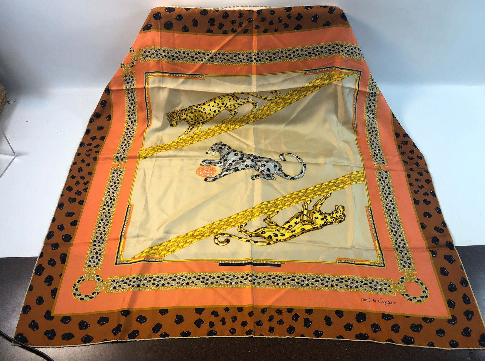 VINTAGE MUST DE CARTIER SILK SCARF: VINTAGE MUST DE CARTIER SILK SCARF ~ PANTHER MOTIF BORDER SURROUNDING CORAL BACKGROUND, SIGNATURE JEWELRY DESIGNS ILLUSTRATED WITH THREE PANTHERS IN THE CENTER, VERY GENTLY USED, ITALIAN MADE SQUARE S