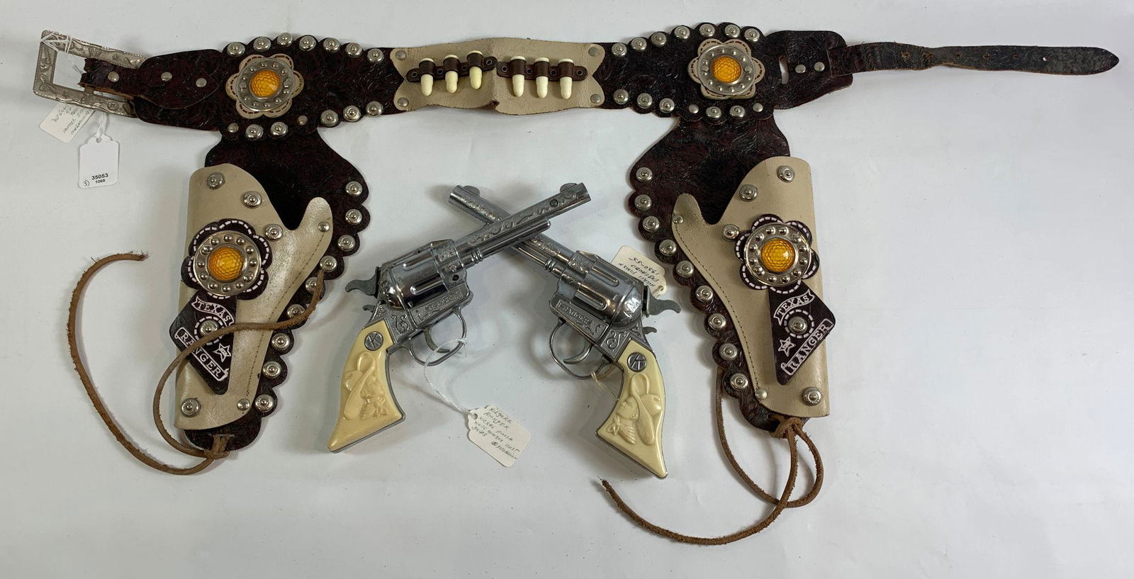VINTAGE TEXAS RANGER BROWN AND TAN LEATHER DOUBLE: VINTAGE TEXAS RANGER BROWN AND TAN LEATHER DOUBLE HOLSTER SET WITH SILVER STUDS, BULLETS, YELLOW JEWELS AND PAIR OF 1950's KILGORE RANGER CAP GUNS WITH NICKEL FINISH AND WHITE COWBOY BUST GRIPS