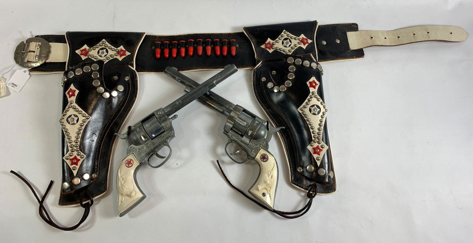 BLACK AND WHITE LEATHER DOUBLE HOLSTER SET, RED STAR: BLACK AND WHITE LEATHER DOUBLE HOLSTER SET, RED STAR AND SILVER STUDS WITH PAIR OF HUBLEY DULL FINISH "COWBOY" CAP GUNS WITH WHITE STEER HEAD GRIPS