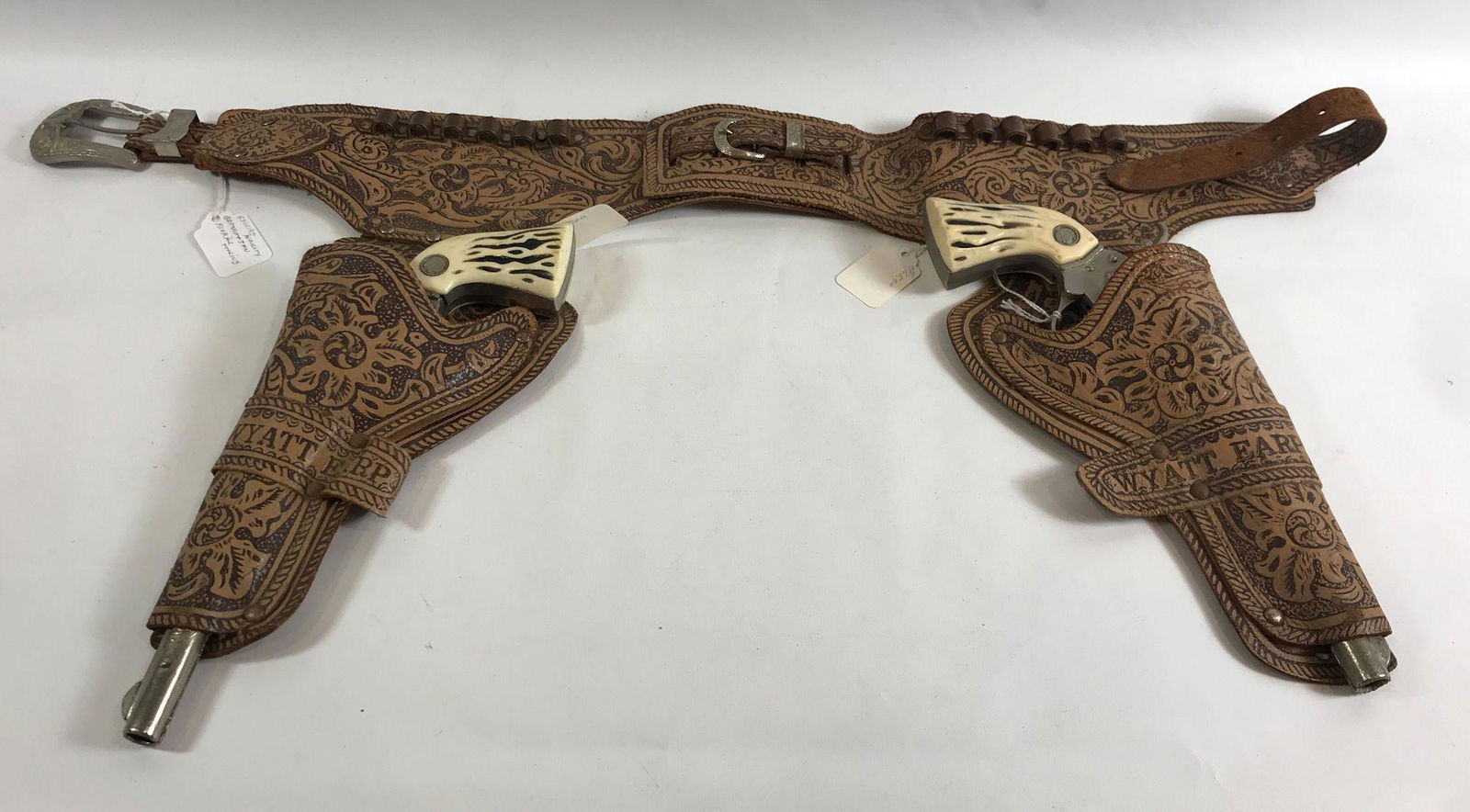 WYATT EARP BROWN TOOLED LEATHER DOUBLE HOLSTER SET WITH: WYATT EARP BROWN TOOLED LEATHER DOUBLE HOLSTER SET WITH BULLET HOLDERS AND PAIR ESQUIRE ACTOY "SPECIAL" 1950's LONG BARREL CAP GUNS