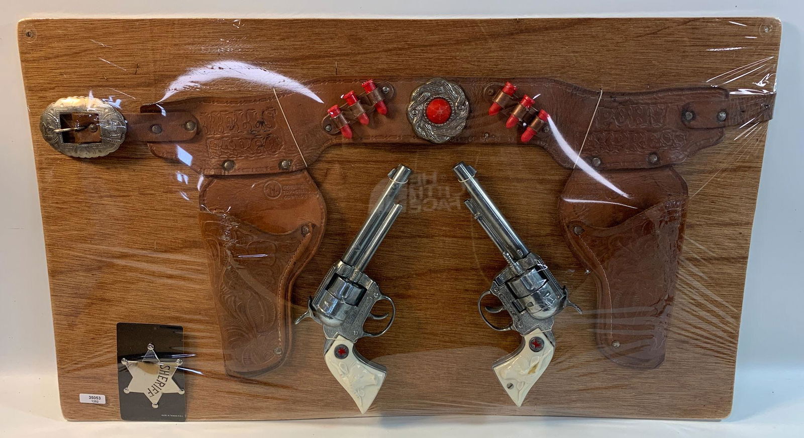 WELLS FARGO "PONY EXPRESS" BROWN TOOLED LEATHER DOUBLE: WELLS FARGO "PONY EXPRESS" BROWN TOOLED LEATHER DOUBLE HOLSTER SET WITH RED BULLETS, COWBOY JR. CAP GUNS WITH WHITE STEER HEAD GRIPS AND SHERIFF BADGE, DISPLAYED ON BOARD