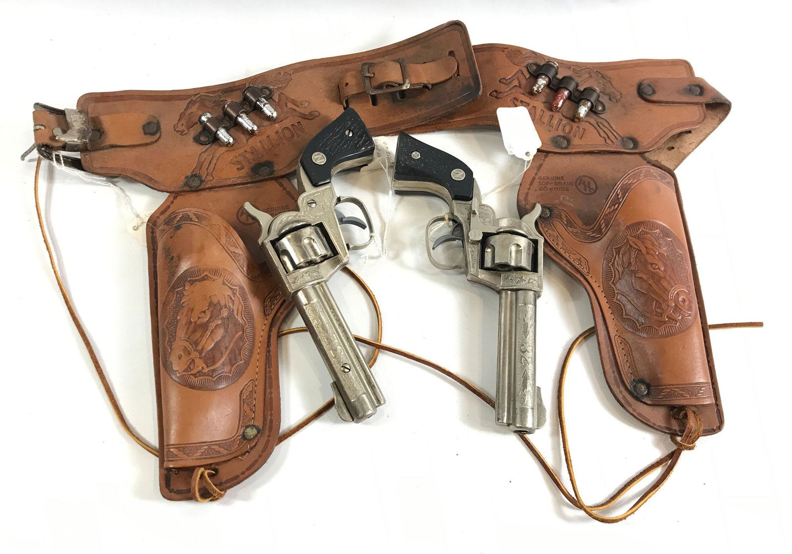 THE TEXAN HOLSTER SET BY HALCO BRAND IN ORIGINAL BOX: THE TEXAN HOLSTER SET BY HALCO BRAND IN ORIGINAL BOX INCLUDING BROWN LEATHER DOUBLE HOLSTERS WITH 1956-1960 NICHOLS STALLION 32 CAP GUNS AND BLACK STAG GRIPS