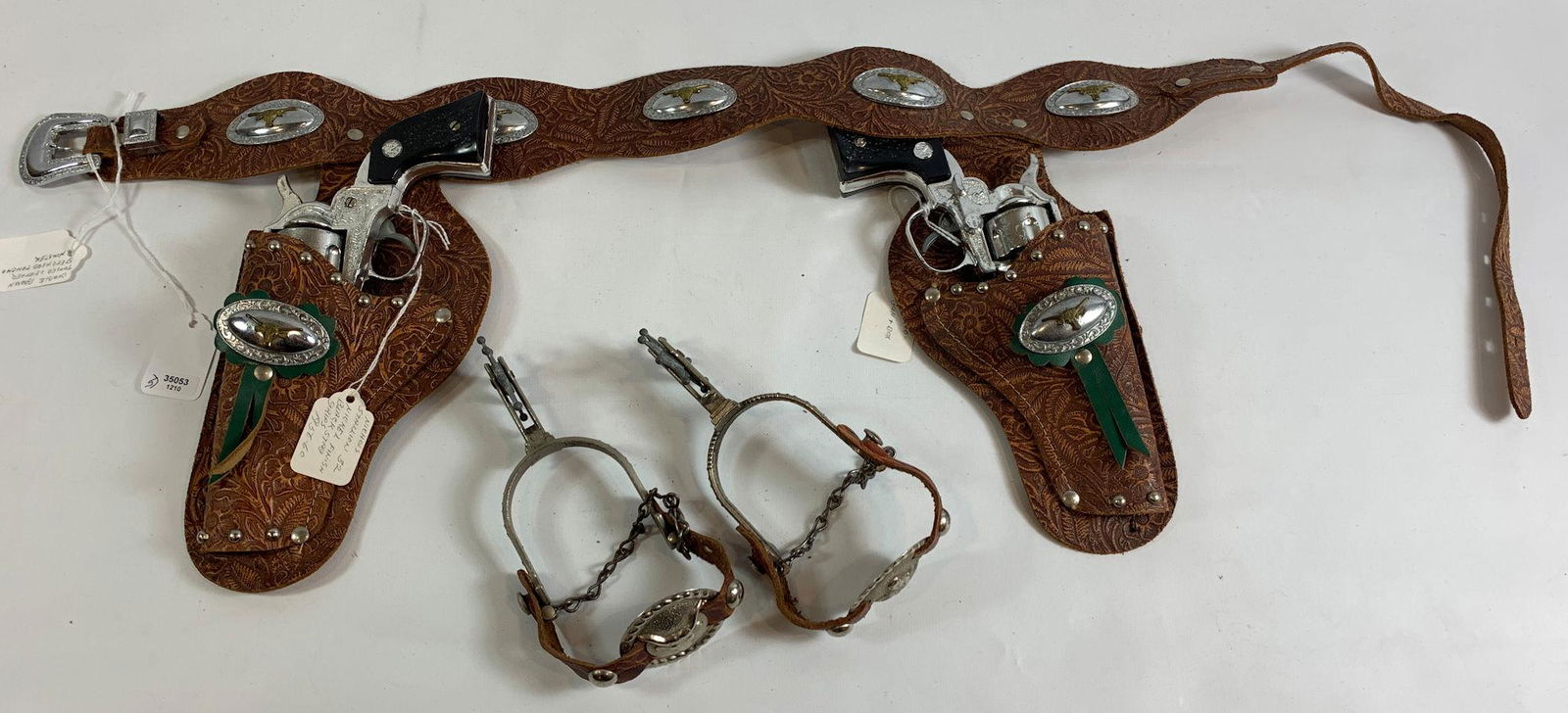 BROWN TOOLED LEATHER DOUBLE HOLSTER SET WITH SPURS AND: BROWN TOOLED LEATHER DOUBLE HOLSTER SET WITH SPURS AND TWO 1956 TO 1960 NICHOLS STALLION 32 CAP GUNS WITH NICKEL FINISH AND BLACK STAG GRIPS