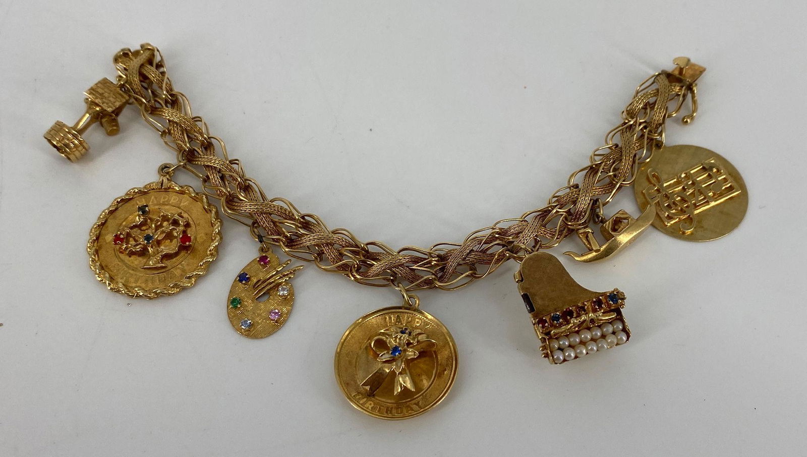 VINTAGE 14KT YELLOW GOLD CHARM BRACELET: VINTAGE 14KT YELLOW GOLD CHARM BRACELET ~ 7.25" MULTI TEXTURE BAND FEATURING INTERWOVEN WHEAT STYLE CHAIN, 14KT YELLOW GOLD CHARMS INCLUDING 14KT YELLOW GOLD PIANO CHARM WITH LOCKET STYLE LIFT TOP, SE