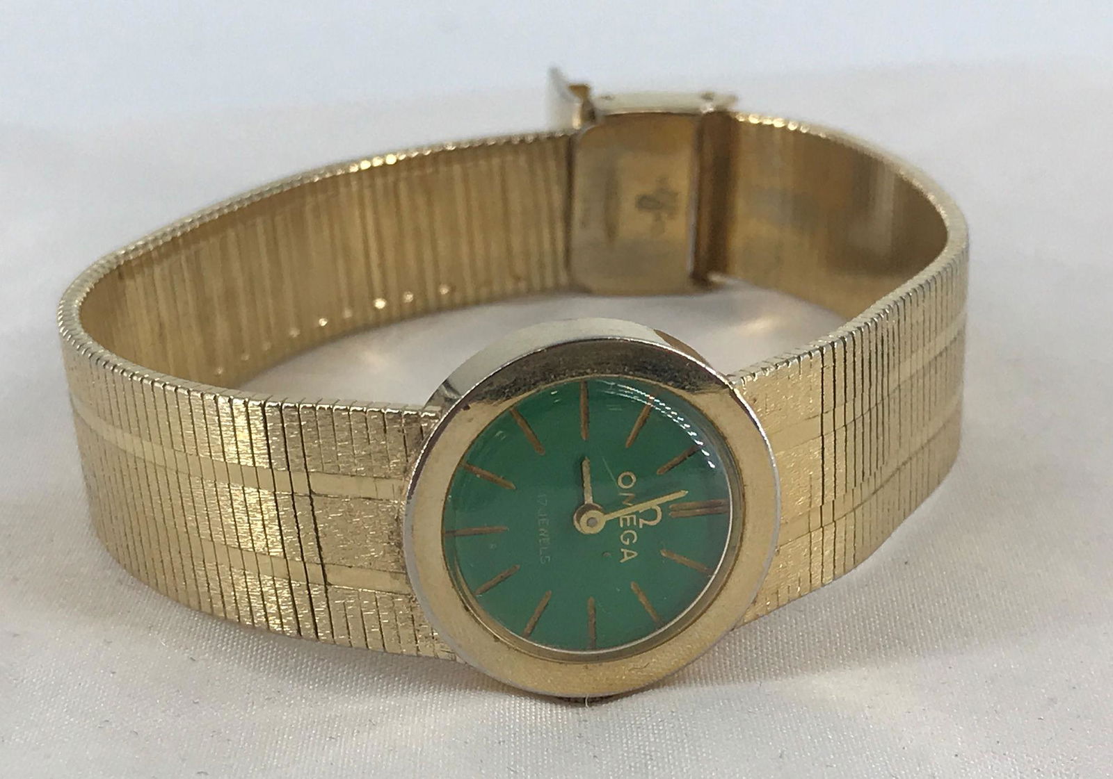 FAKE OMEGA WRIST WATCH: FAKE OMEGA WRIST WATCH ~ BAND WITH PINSTRIPE DESIGN. BRUSHED AND POLISHED METAL FINISHES. 0.625" GREEN COLOR FACE WITH STRAIGHT HANDS AND INDICATORS (GOLD TONE). WINDS, SETS AND TICKS AT TIME OF LISTI