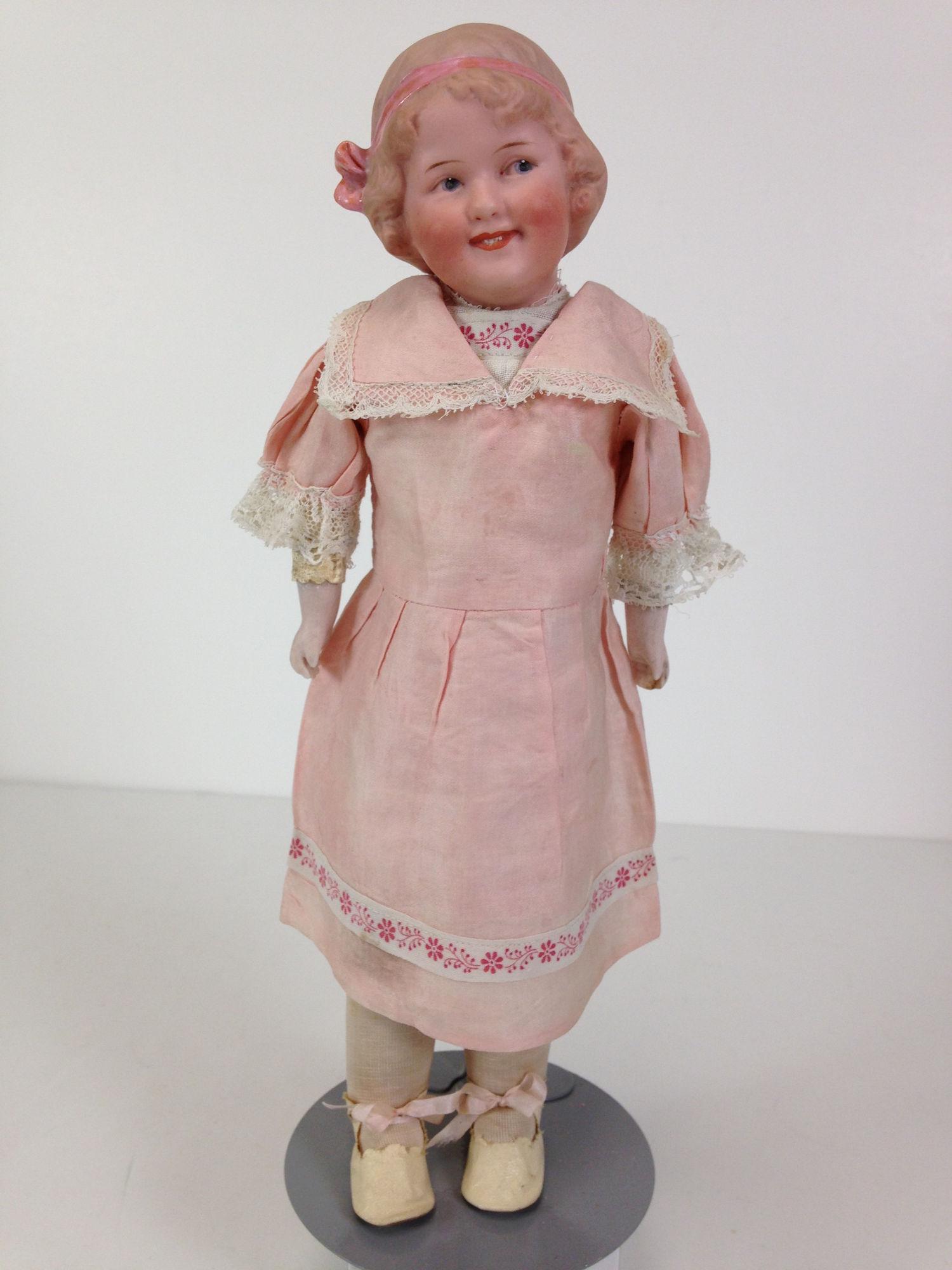 13" GBR. HEUBACH BISQUE SHOULDER HEAD "COQUETTE".: 13" GBR. HEUBACH BISQUE SHOULDER HEAD "COQUETTE". MOLDED AND PAINTED HAIR, PINK HAIR RIBBON & BOW, INTAGLIO EYES AND OPEN/CLOSED MOUTH WITH MOLDED TEETH. ON KID BODY WITH BISQUE LOWER ARMS WEARING PIN