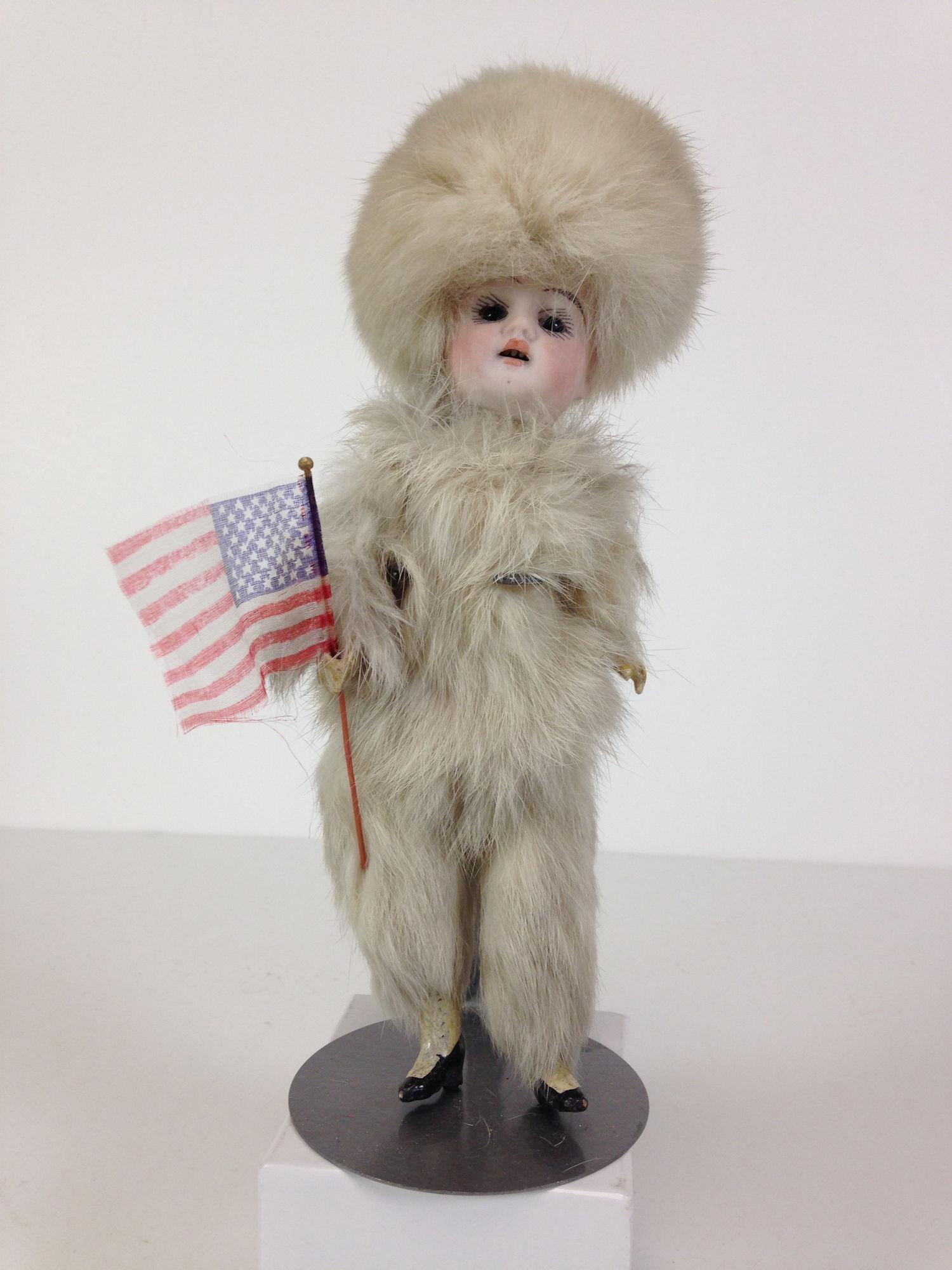 9" (OVERALL) GERMAN BISQUE HEAD SNOW/FUR BABY. SOCKET: 9" (OVERALL) GERMAN BISQUE HEAD SNOW/FUR BABY. SOCKET HEAD WITH STATIONARY GLASS EYES AND OPEN MOUTH WITH TEETH. ON FIVE-PIECE COMPOSITION BODY WITH PAINTED SHOES. WEARS RABBIT FUR HAT AND SUIT AND HO