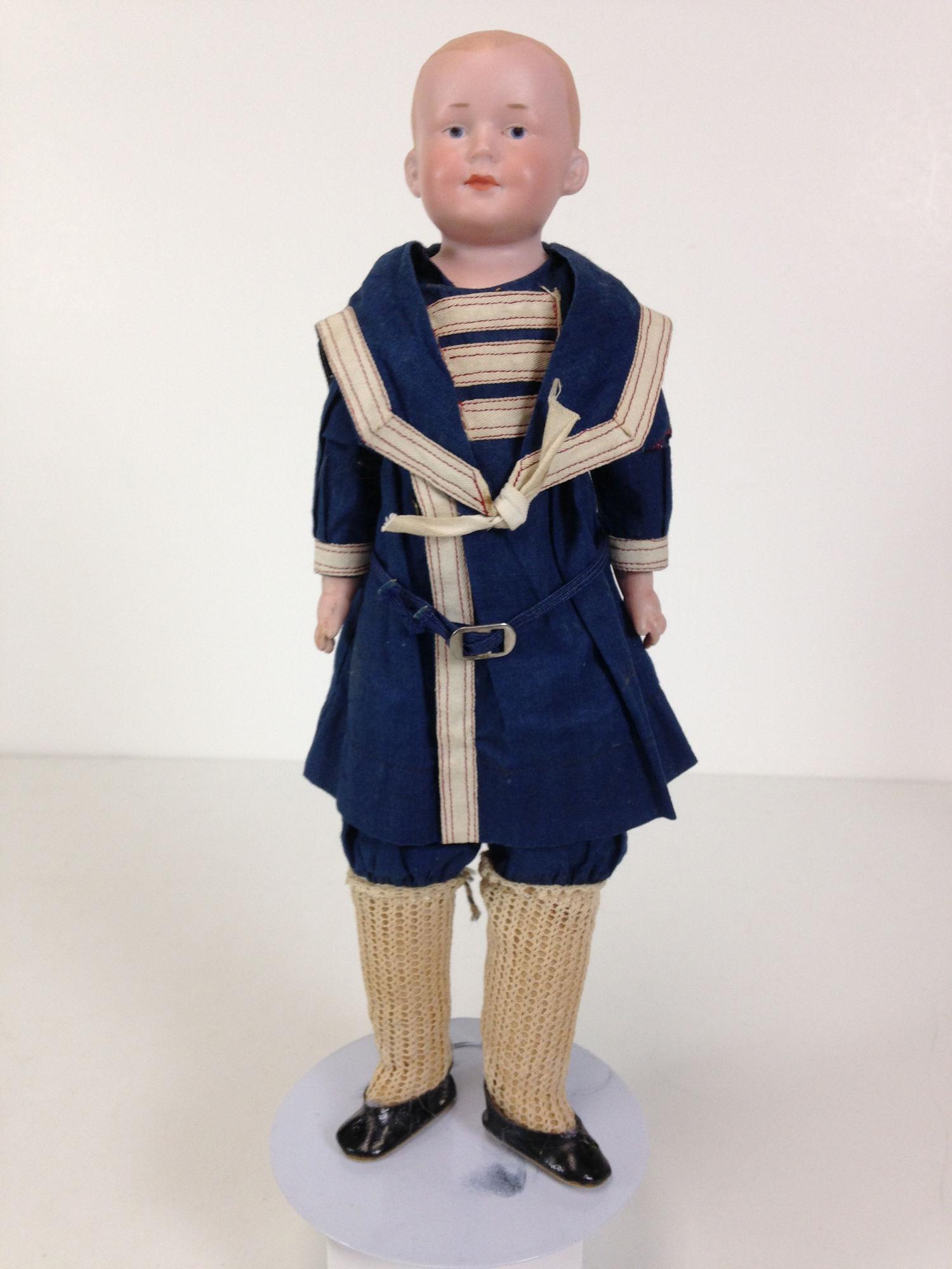 12" A.M. 600 BISQUE SHOULDER HEAD CLOSED MOUTH: 12" A.M. 600 BISQUE SHOULDER HEAD CLOSED MOUTH CHARACTER. MOLDED AND PAINTED HAIR AND INTAGLIO EYES. ON KID BODY WITH BISQUE LOWER ARMS AND MUSLIN LOWER LEGS WEARING DARK BLUE SAILOR OUTFIT.