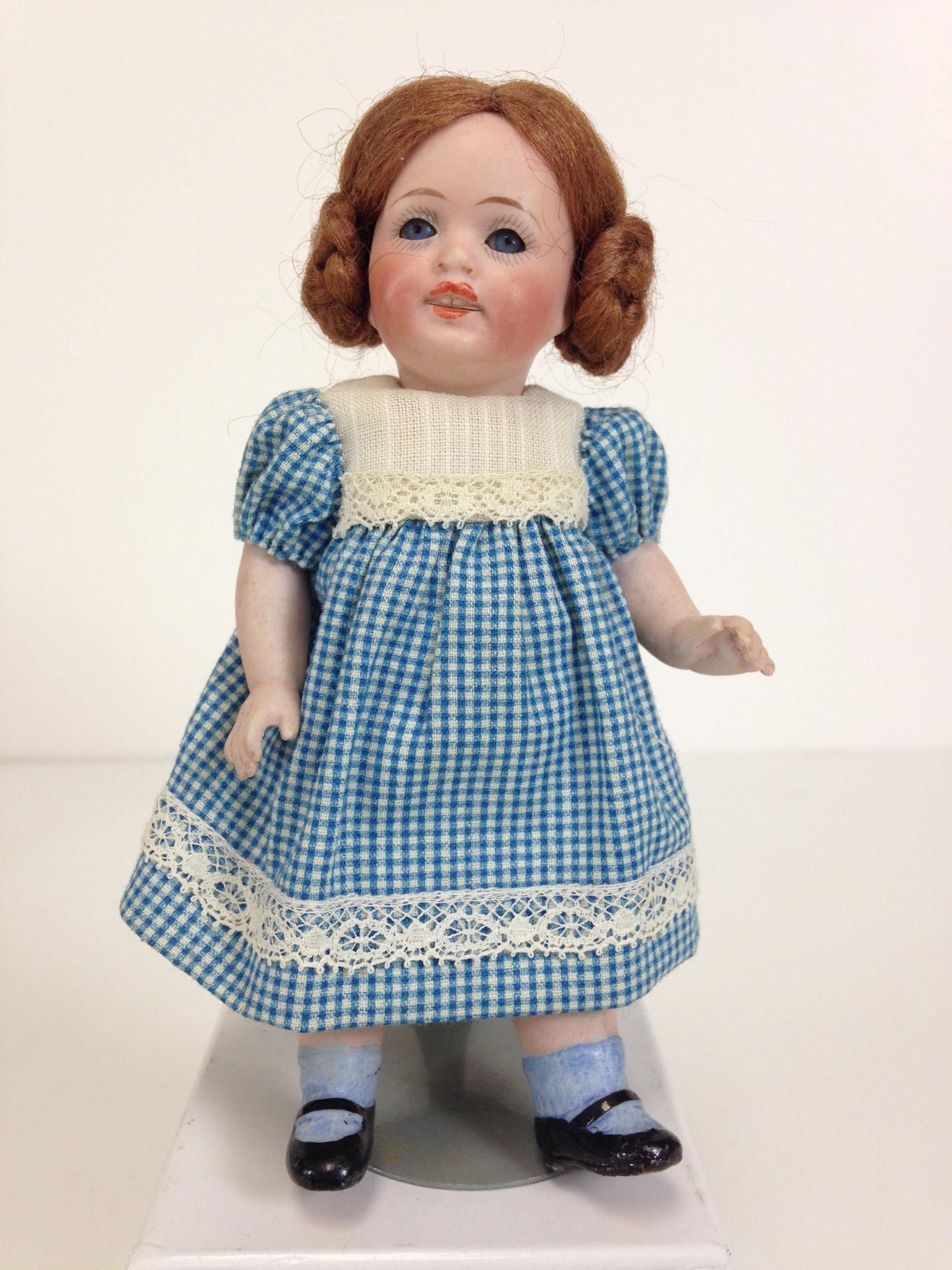 5Â½" GERMAN ALL BISQUE CHARACTER CHILD. MOHAIR WIG,: 5½" GERMAN ALL BISQUE CHARACTER CHILD. MOHAIR WIG, GLASS SLEEP EYES AND OPEN MOUTH WITH TEETH. ON FIVE-PIECE BODY WITH MOLDED AND PAINTED BLUE SOCKS AND BLACK MARY JANE SHOES. WEARS BLUE & WHIT