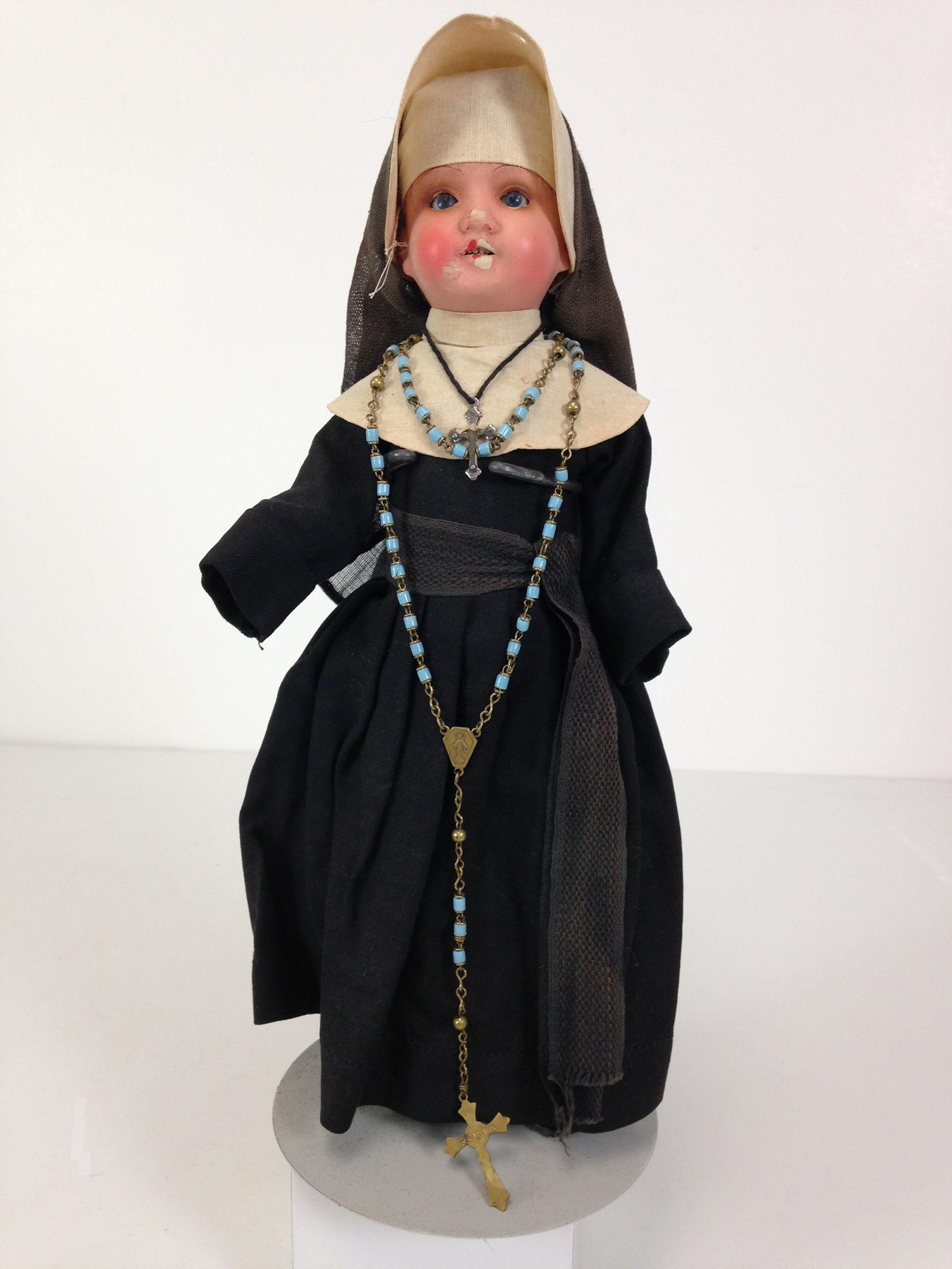 12" A.M. 390 PAINTED BISQUE DOLL DRESSED AS NUN.: 12" A.M. 390 PAINTED BISQUE DOLL DRESSED AS NUN. SOCKET HEAD WITH SET GLASS EYES AND OPEN MOUTH WITH TEETH, ON FIVE-PIECE COMPOSITION BODY. WEARS LAYERED NUN'S BLACK COTTON HABIT, UNDERGARMENTS, SHOES