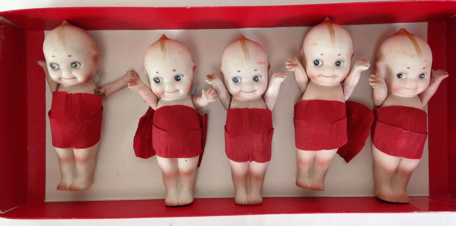 (5) 6" NIPPON ALL BISQUE KEWPIE TYPES WITH ONE-PIECE: (5) 6" NIPPON ALL BISQUE KEWPIE TYPES WITH ONE-PIECE HEAD, TORSO AND LEGS; EACH WEAR RED CREPE PAPER WRAPPED AROUND THEIR MIDDLES.
