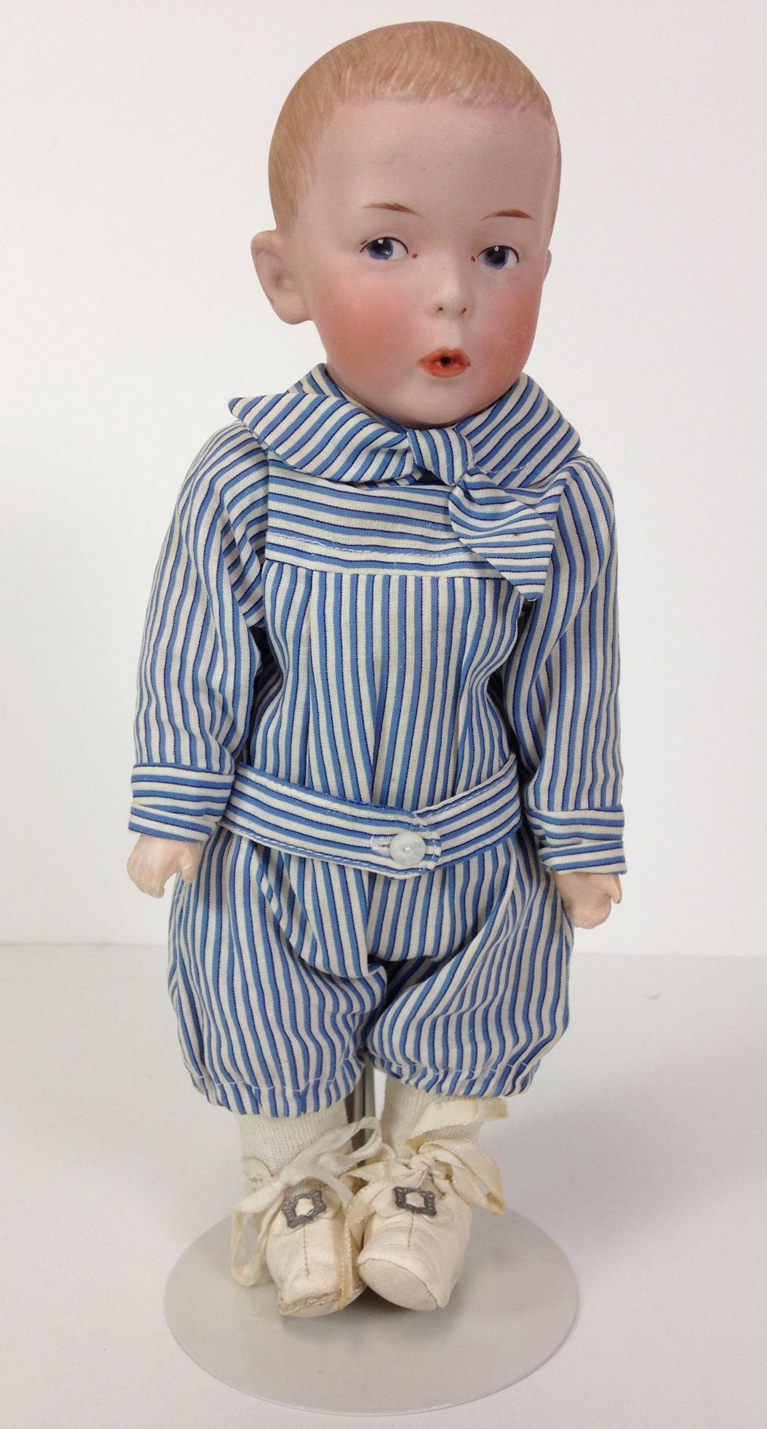 13" GBR. HEUBACH 8774 BISQUE HEAD "WHISTLER". FLANGE: 13" GBR. HEUBACH 8774 BISQUE HEAD "WHISTLER". FLANGE NECK HEAD, SOLID DOME WITH MOLDED AND PAINTED HAIR, INTAGLIO EYES AND OPEN DRAWN TOGETHER MOUTH. ON DISK JOINTED CLOTH BODY WITH BISQUE LOWER ARMS.