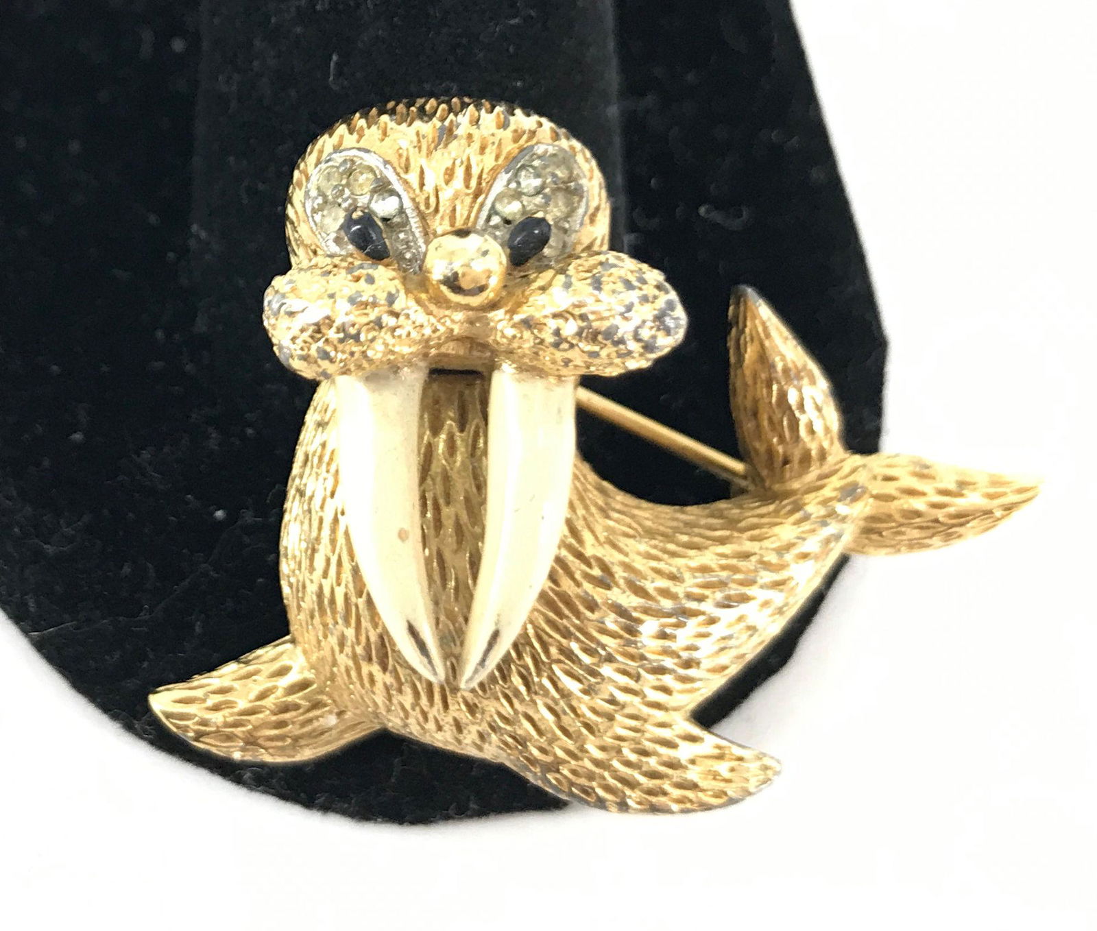 WALRUS PIN: WALRUS PIN ~ GOLD TONE METAL. 1.625" IN WIDTH. SIGNED JOMAZ. TEXTURED METAL FINISH. CLEAR DIAMANTE STONE ROUNDS ACCENTING EYES. VINTAGE AGE.