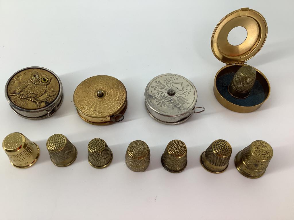 Box lot of yellow metal thimbles, tape measures and a: Box lot of yellow metal thimbles, tape measures and a thimble case.