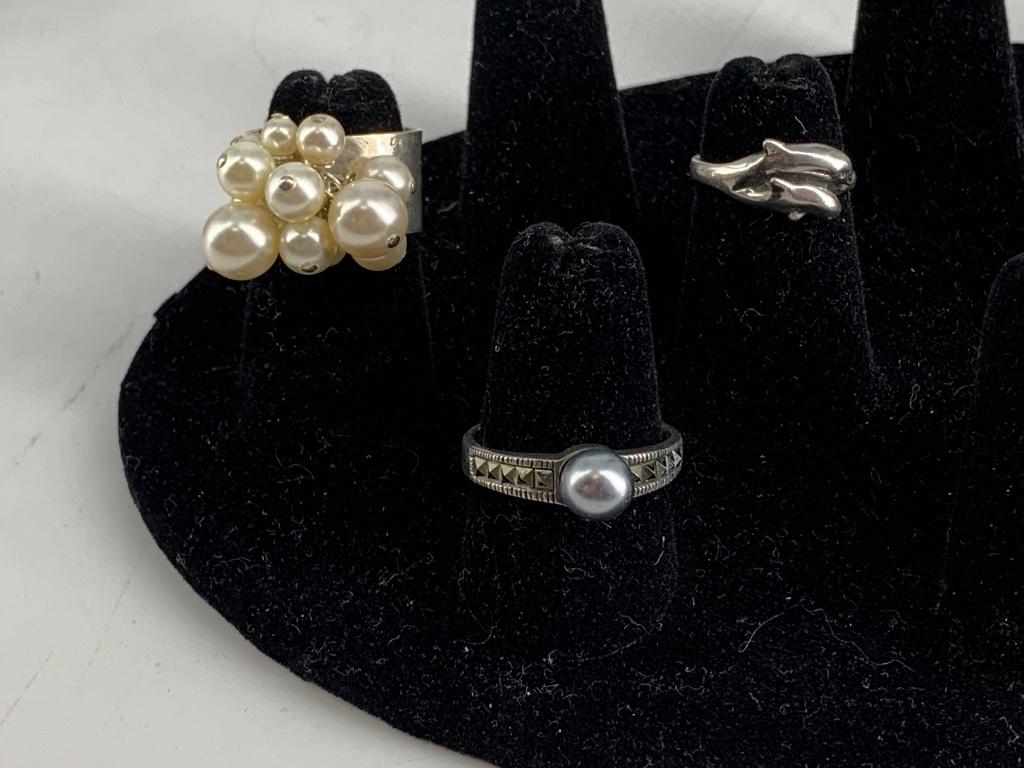 Three Sterling Rings: Three Sterling Rings Faux pearl cluster, faux pearl and marcasite, and twin dolphin designs. Stamped and/or tested 925. 0.47 troy ounces total weight. Sizes 4.5 - 8.5. Two rings signed.