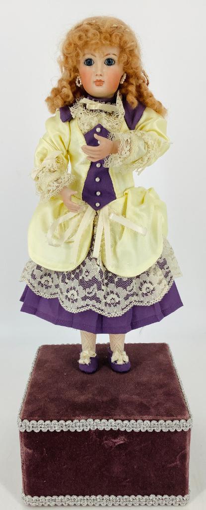 Reproduction Jumeau automaton. Mohair wig, stationary: Reproduction Jumeau automaton. Mohair wig, stationary glass eyes, closed mouth, on stationary body affixed to a velvet covered box. When wound, music plays and doll's head and arms move up and down. O