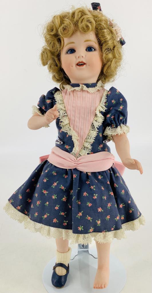 13" artist made all porcelain Shirley Temple doll. On: 13" artist made all porcelain Shirley Temple doll. On five-piece body wearing dark blue dress with pink floral print. Has one shoe.