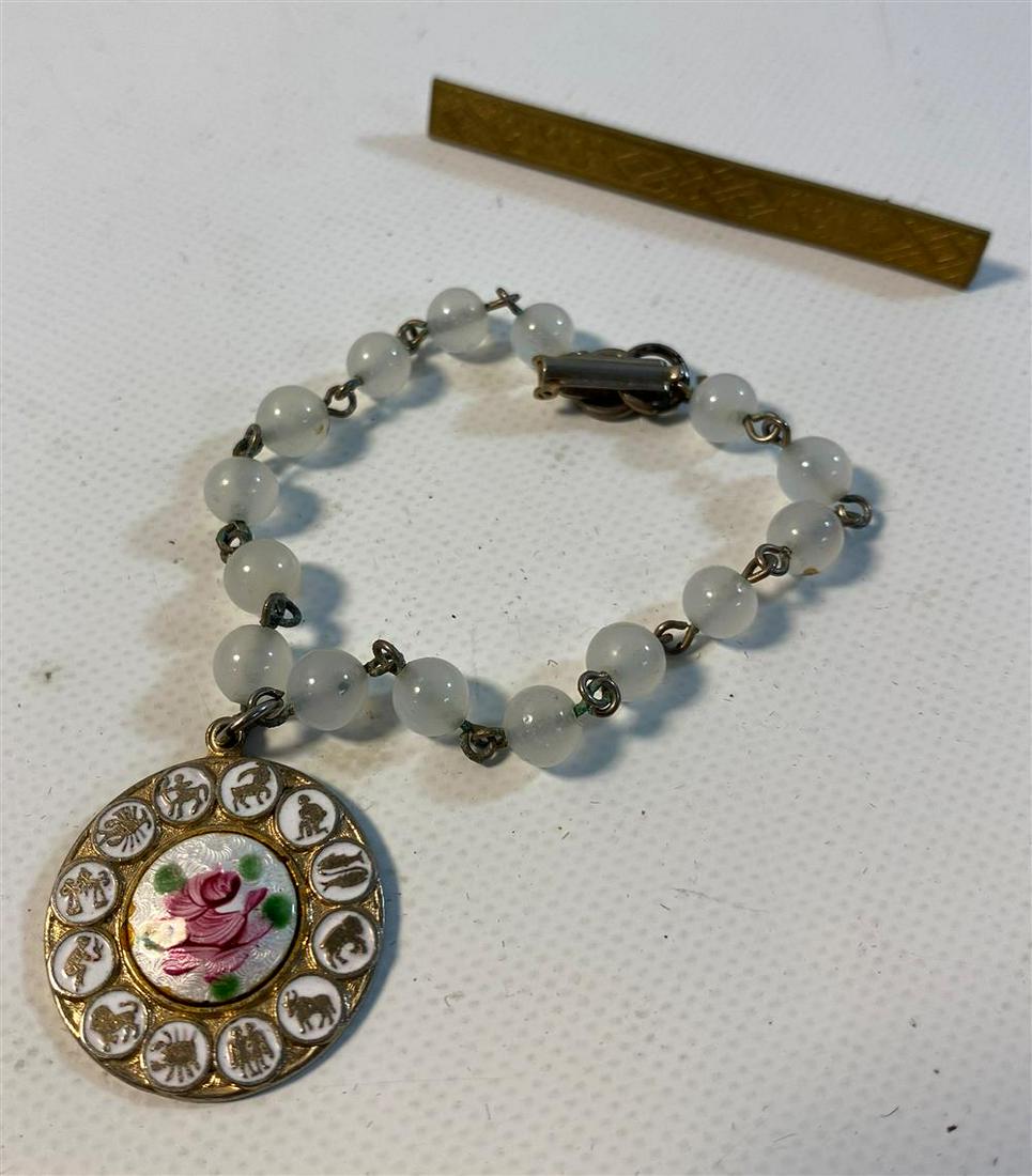 LOT OF VINTAGE JEWELRY: Lot of Vintage Jewelry Vintage 2.375" embossed gold tone metal bar pin with floral design (unsigned). 6.5" bracelet with foldover clasp, white beads (6.5mm), and white enameled 1" disk pendants with z