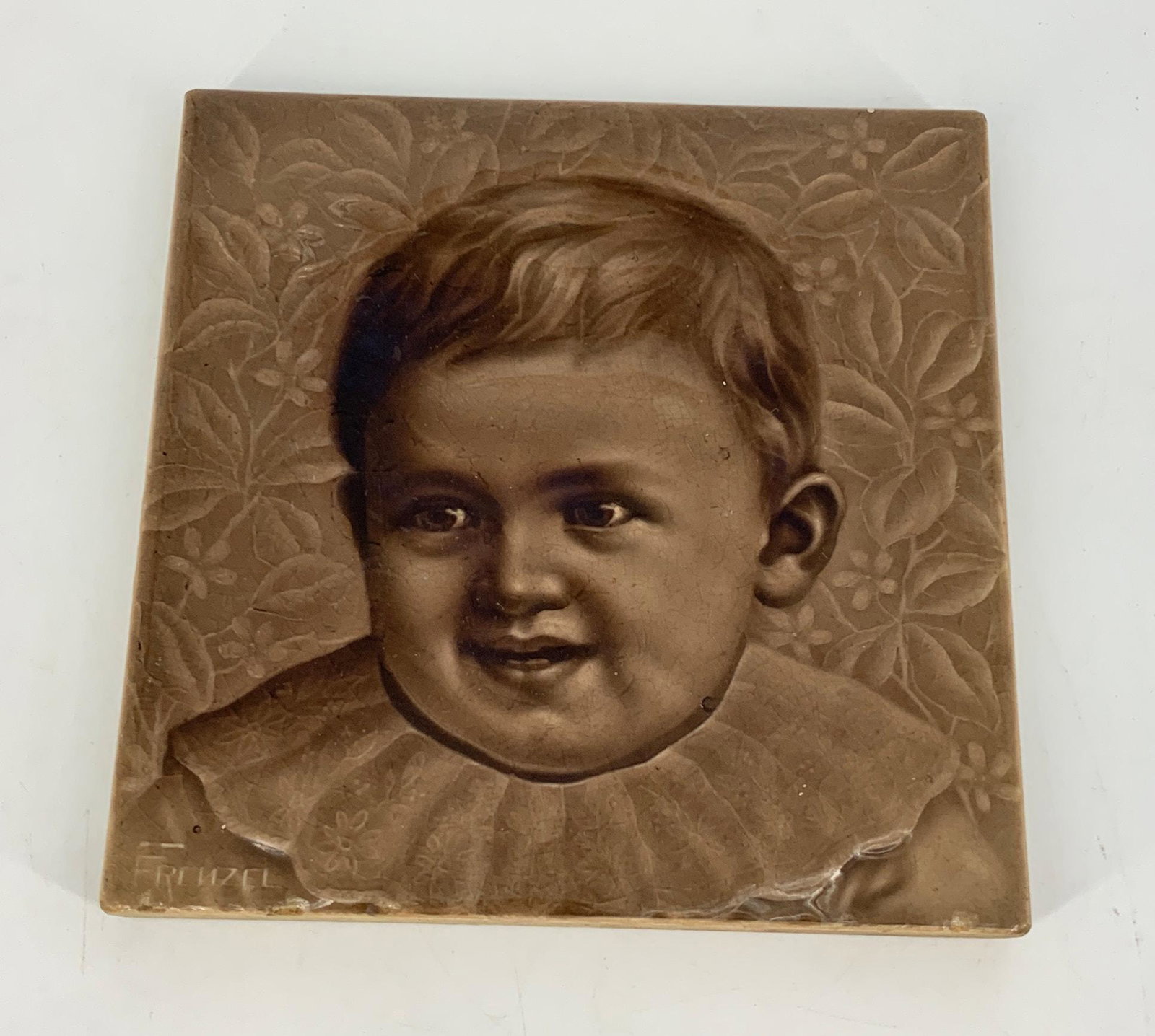 A.E. Tile with baby 6" X 6". Zanesville, Ohio pottery.,: A.E. Tile with baby 6" X 6". Zanesville, Ohio pottery.