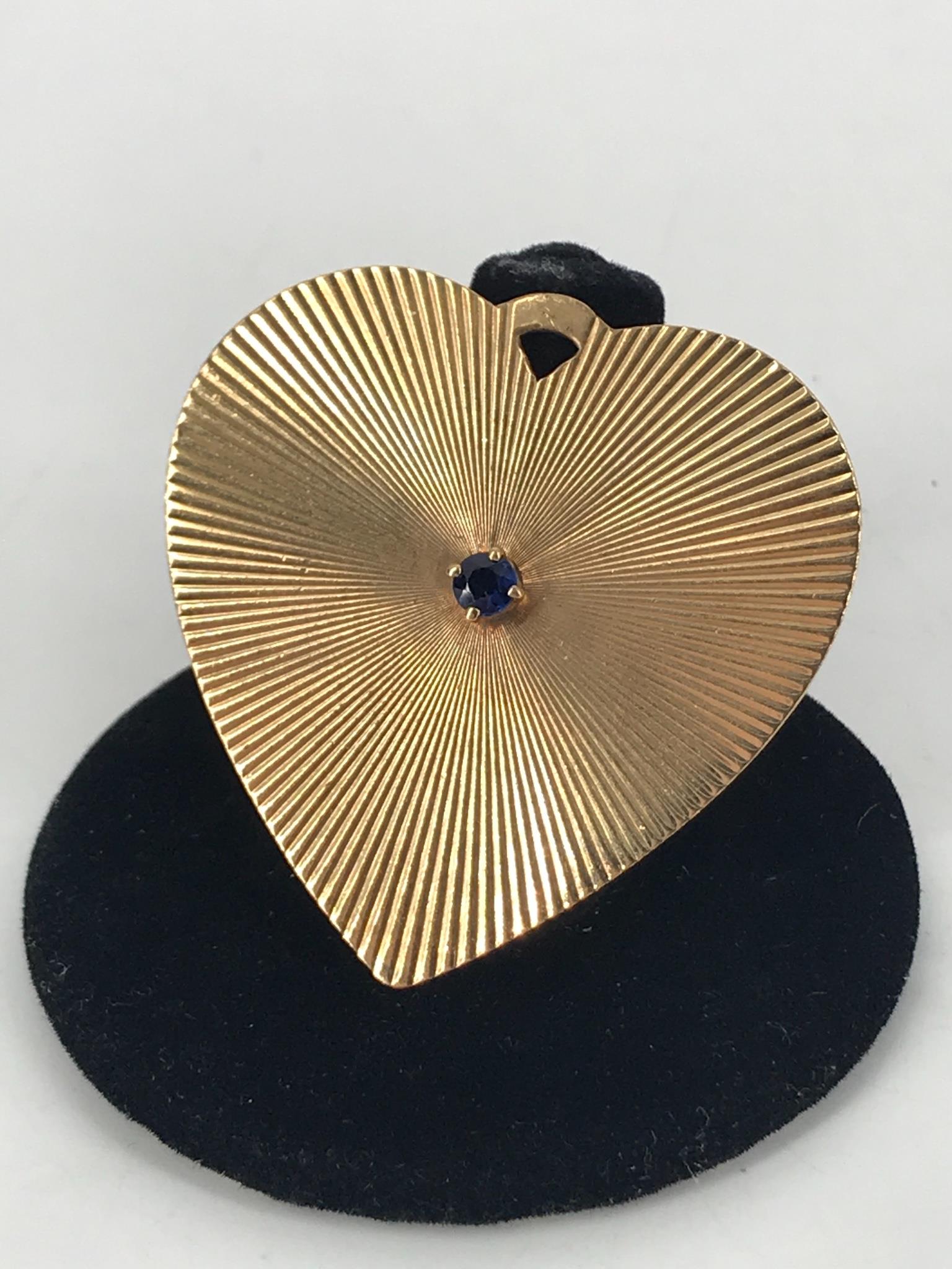 14kt Yellow Gold Heart Charm: 14kt Yellow Gold Heart Charm 1.54Ã® in length featuring a radiating design accented with a man made blue gemstone in the center featuring a personal engraving on the reverse, stamped and tested (13.