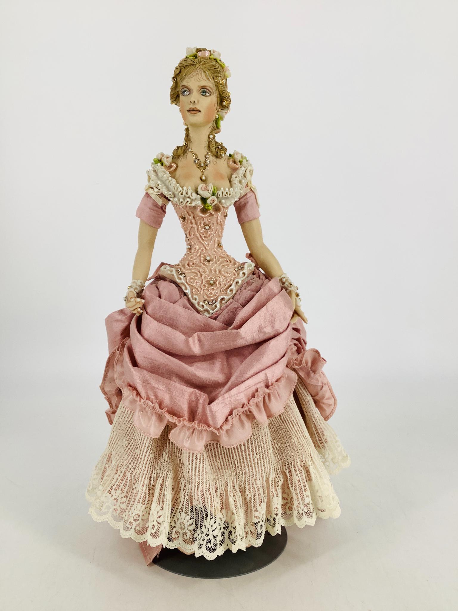 Porcelain artist doll by Kathy Redmond. 14" doll with: Porcelain artist doll by Kathy Redmond. 14" doll with elaborately decorated head/torso with cloth jointed porcelain arms and legs, applied silk and lace skirt.