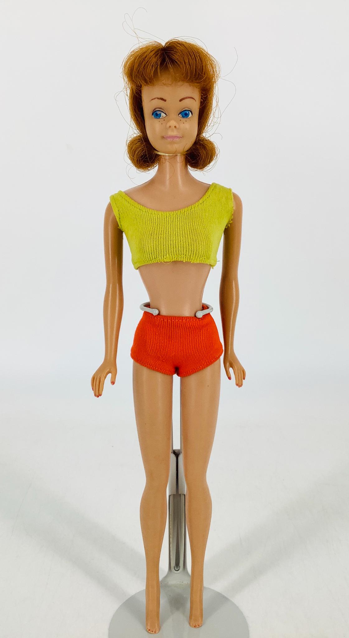 Midge, who has red hair and freckles & comes with: Midge, who has red hair and freckles & comes with original bathing suit, black stand and booklet in original Midge box. Midge has a rubberband around neck to hold curl in, however this is not how she